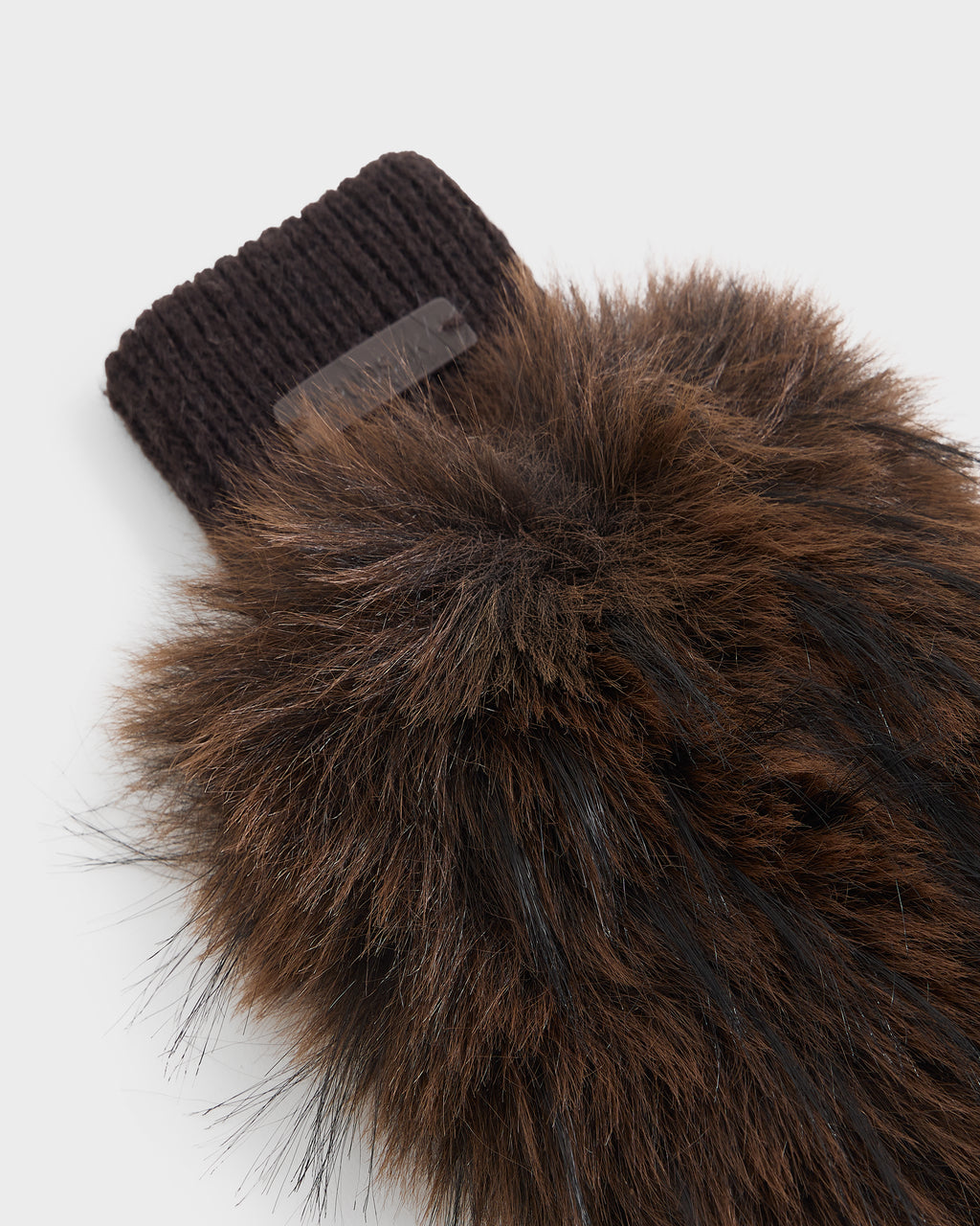 A close-up of the Rudsak LIA - 8425007 Mix Espresso mitten reveals its plush brown faux fur and black ribbed knit cuff, highlighted by a subtle dark tag—an elegant, fingerless accessory that adds cozy sophistication peeking from beneath any women’s sleeve.
