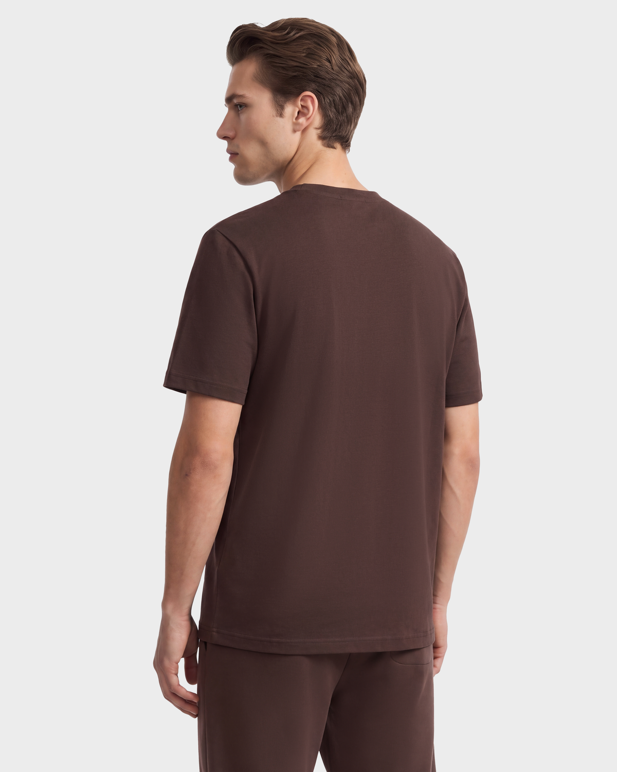 A man seen from behind wearing a dark brown GRANT - 6525036 Espresso crewneck t-shirt and matching shorts.