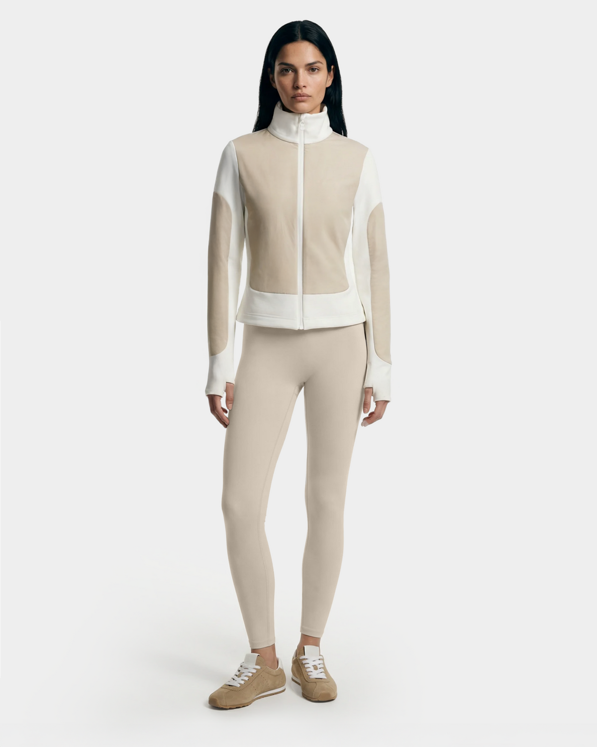 A woman with long dark hair wears Rudsak’s GRANADA - 8126023 Vanilla sweater jacket, matching beige leggings, and beige sneakers while standing against a plain white background.