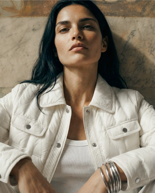 Woman wearing a white jacket against a textured wall