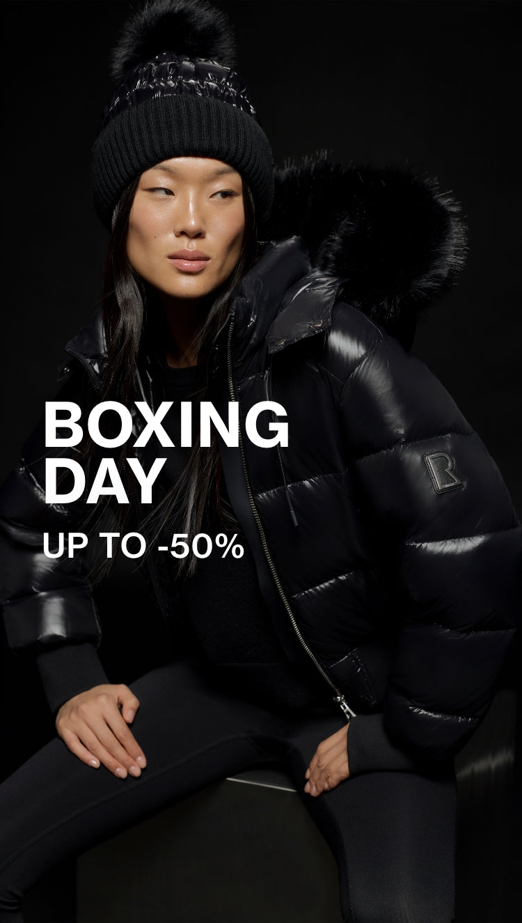 Person wearing a black coat and hat with 'Boxing Day' sale text on a dark background