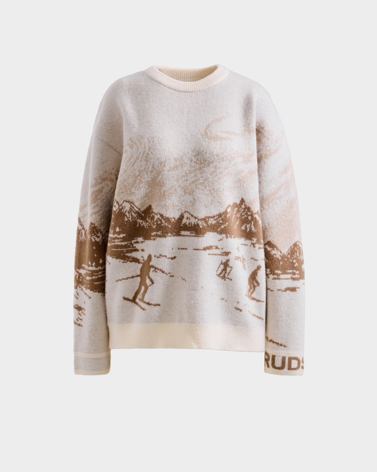 The Rudsak IZZY - 9525557 Iceland W is a cream and light brown unisex knit sweater with a mountain scene, skiers, trees, clouds, and "RUDE" near the left cuff, displayed on a plain background.