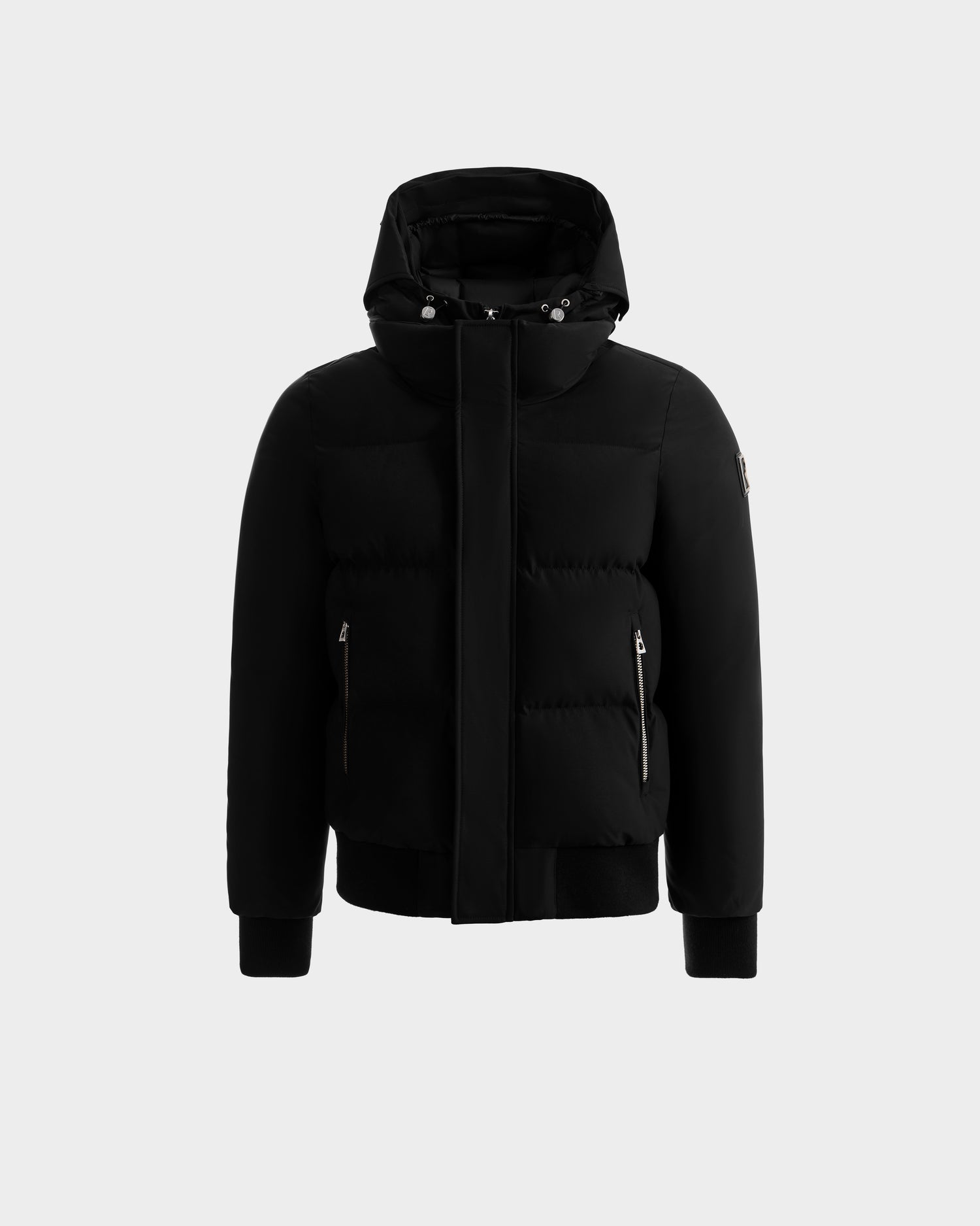 The JORDY - 6125692 Black puffer jacket by Rudsak features a hood, front zipper, snap buttons, and two side zip pockets, shown against a plain light gray background.