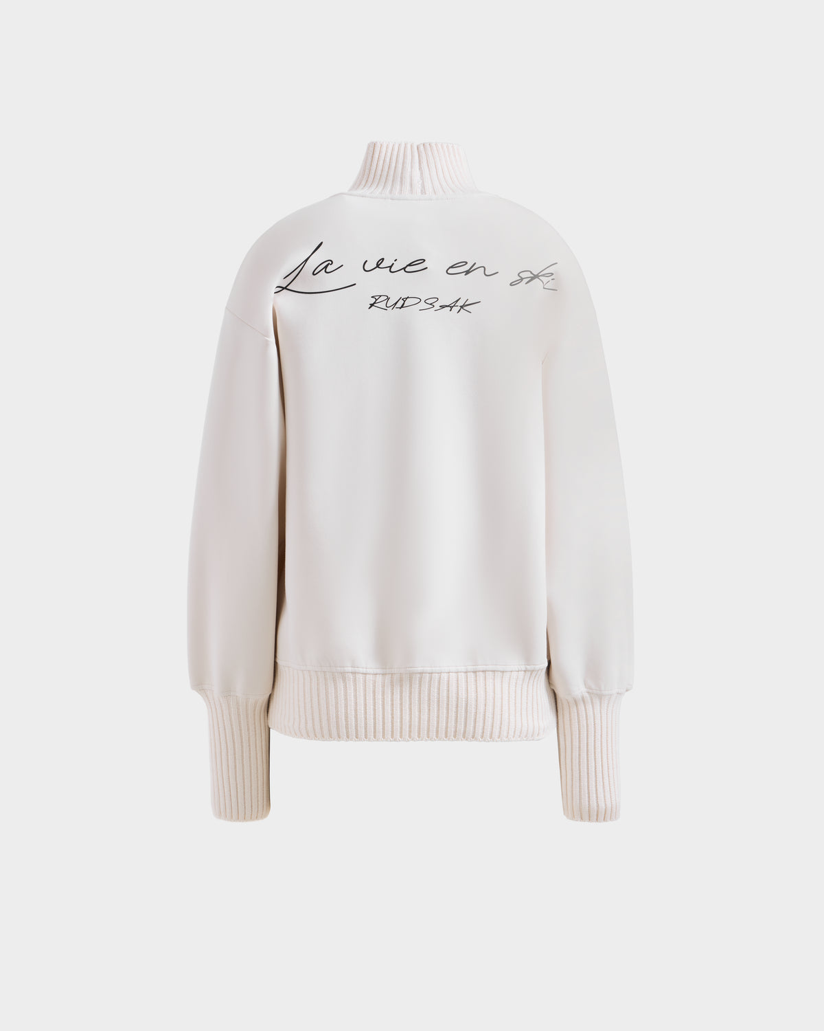The JOYCE - 8525647 Vanilla by Rudsak is a light pink women's cotton blend long-sleeve ski sweater with ribbed cuffs and hem, featuring handwritten "La vie en rose" and "BUDSAK" on the back, shown on a plain white background.