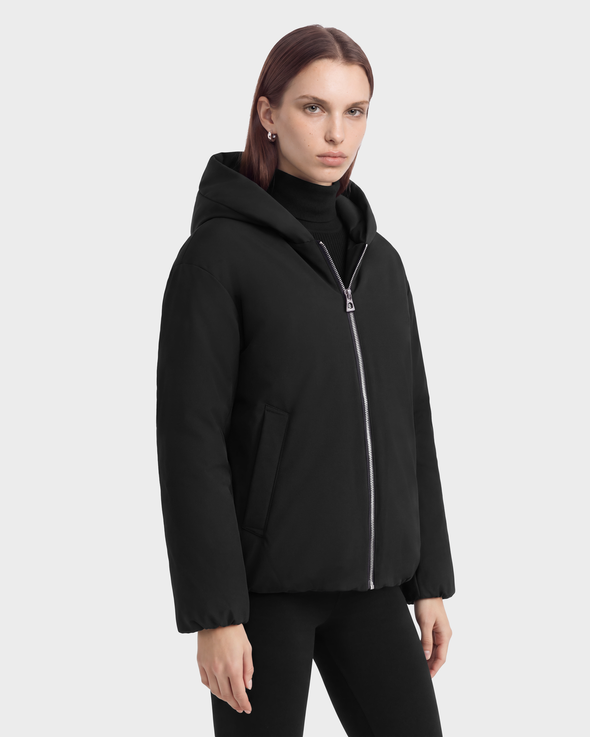 A person wears a black KATHLEEN - 8126764 Black hooded puffer jacket with a silver front zipper.