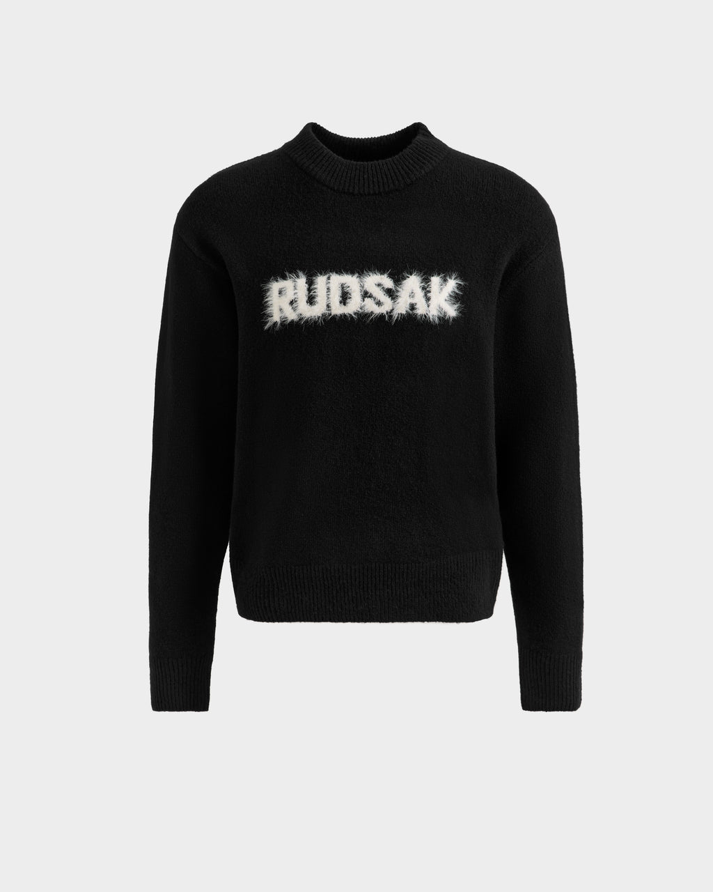 The KINLEY - 9525555 Black W unisex crewneck sweater by Rudsak features white, fuzzy-textured “RUDSAK” lettering across the chest—a cozy and stylish knit essential, shown on a plain light grey background.