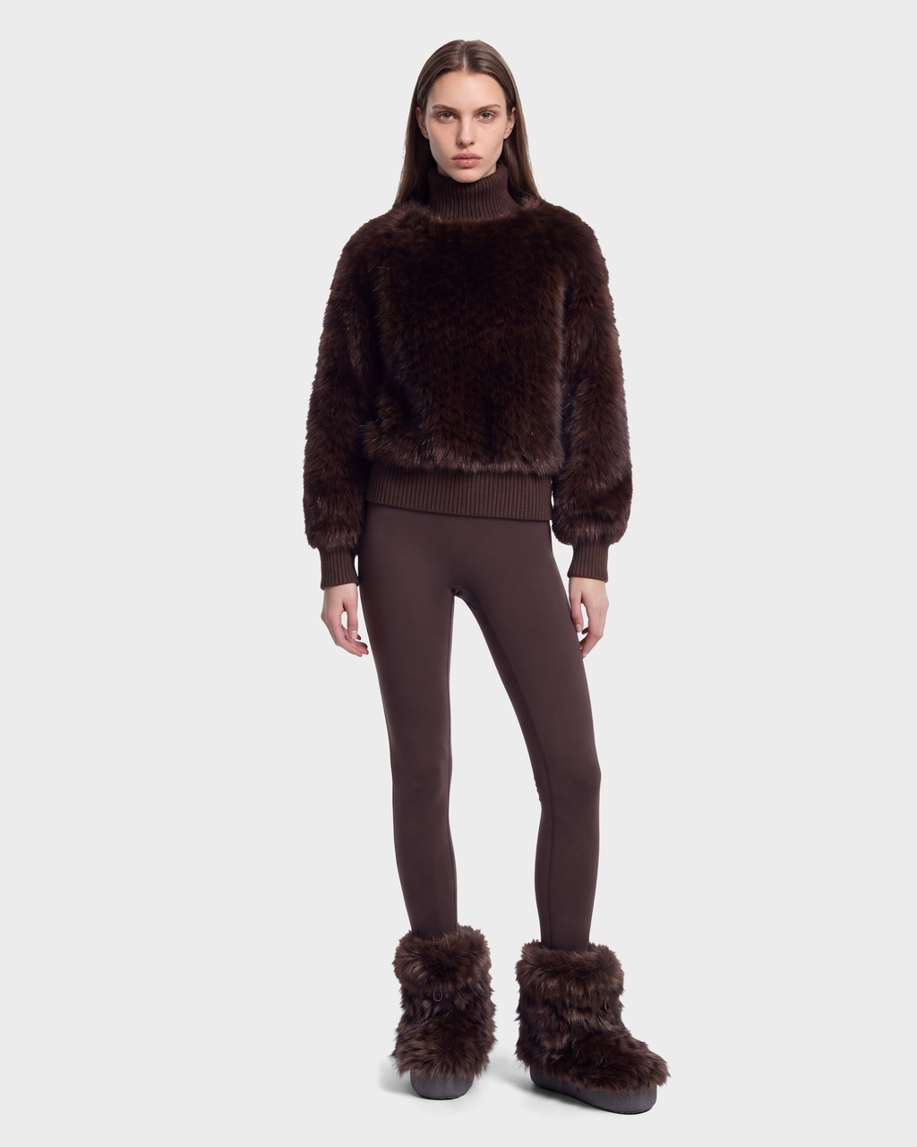 A model wearing the LAYLA F - 8525630 Mix Expresso dark brown cable-textured faux-fur turtleneck sweater with ribbed cuffs, matching leggings, and dark brown faux-fur trimmed winter boots for an après-ski style.