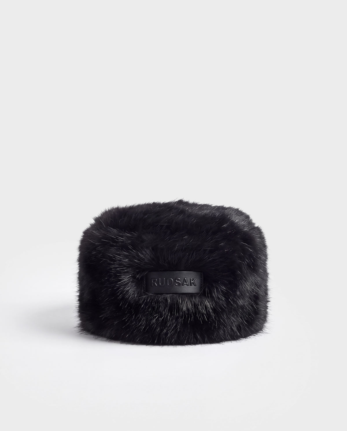 Black LORETTA - 8426503 faux fur pillbox hat featuring a central leather patch embossed with the word RUDSAK.