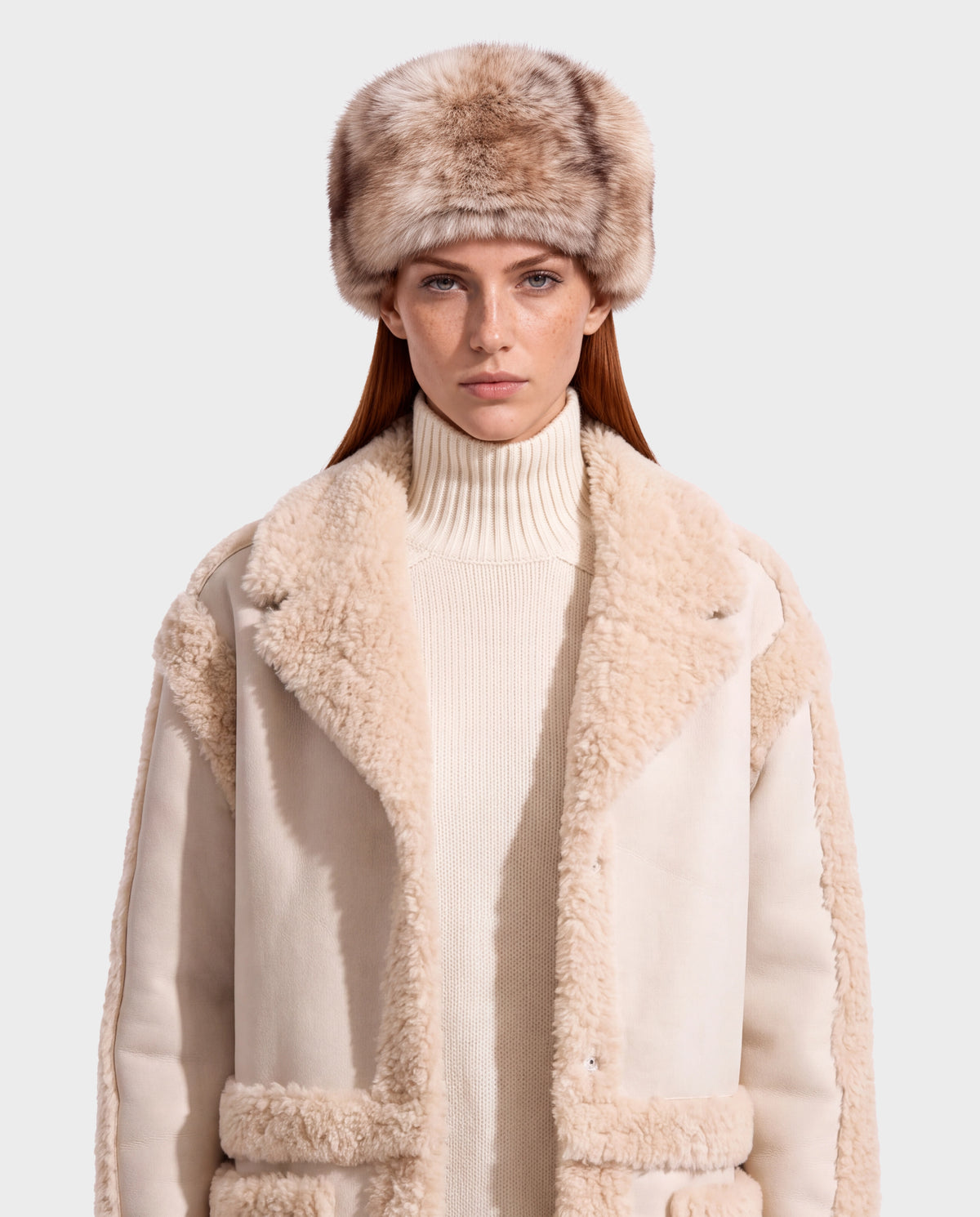 A person wearing a LORETTA - 8426503 Mix Vanilla cream-colored shearling-lined coat over a turtleneck sweater and a faux-fur hat.