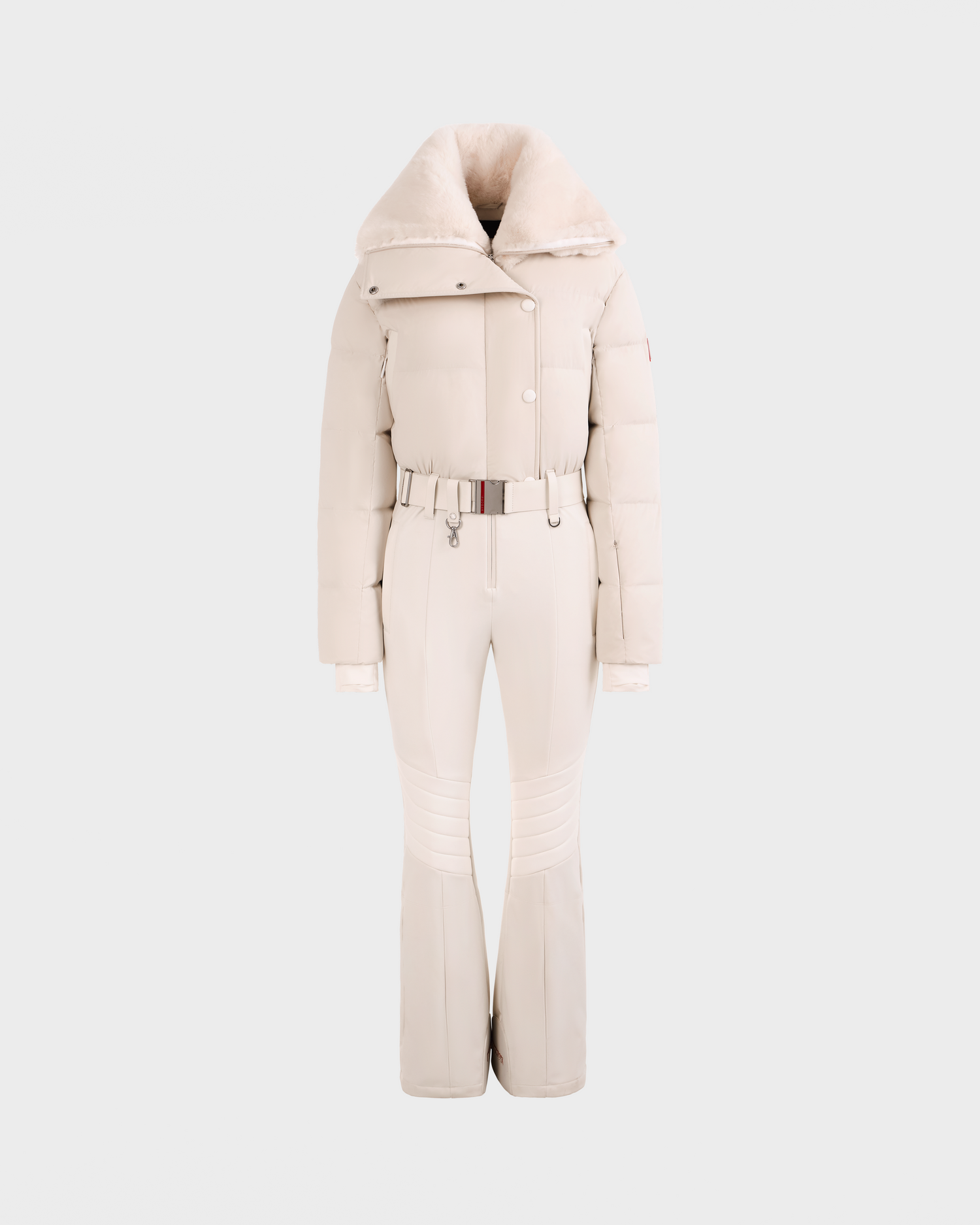 The Rudsak LOVE - 8124724 Vanilla is a stylish cream women’s ski suit with a belted waist, padded jacket, high faux fur collar, and fitted pants with ribbed knees, shown against a plain light background.