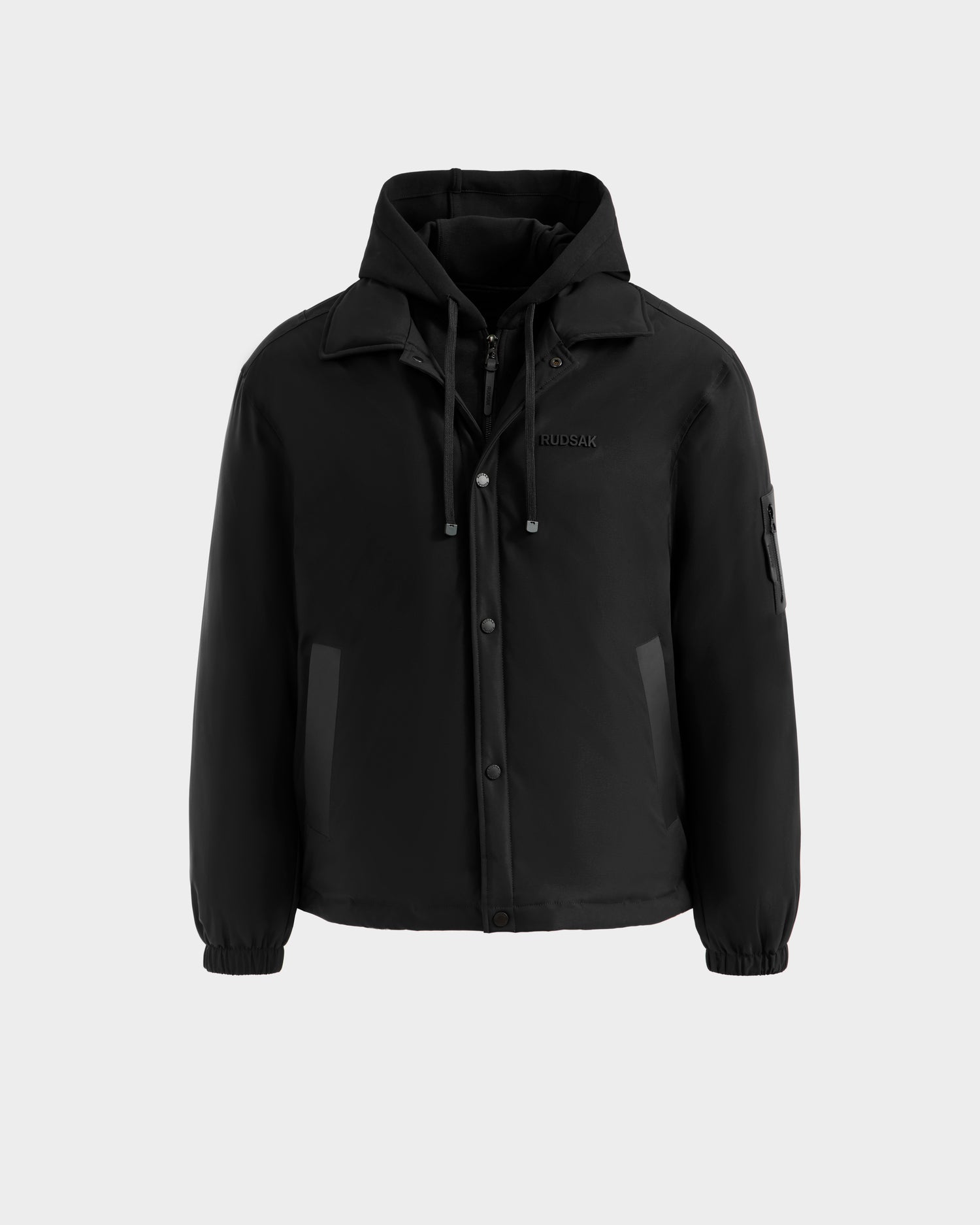 The Rudsak LUCA - 6125009 Black is a weather-resistant men’s jacket featuring a front zipper with snap buttons, drawstring hood, two side and one arm pocket, elastic cuffs, high collar, and lightweight insulation for comfort.