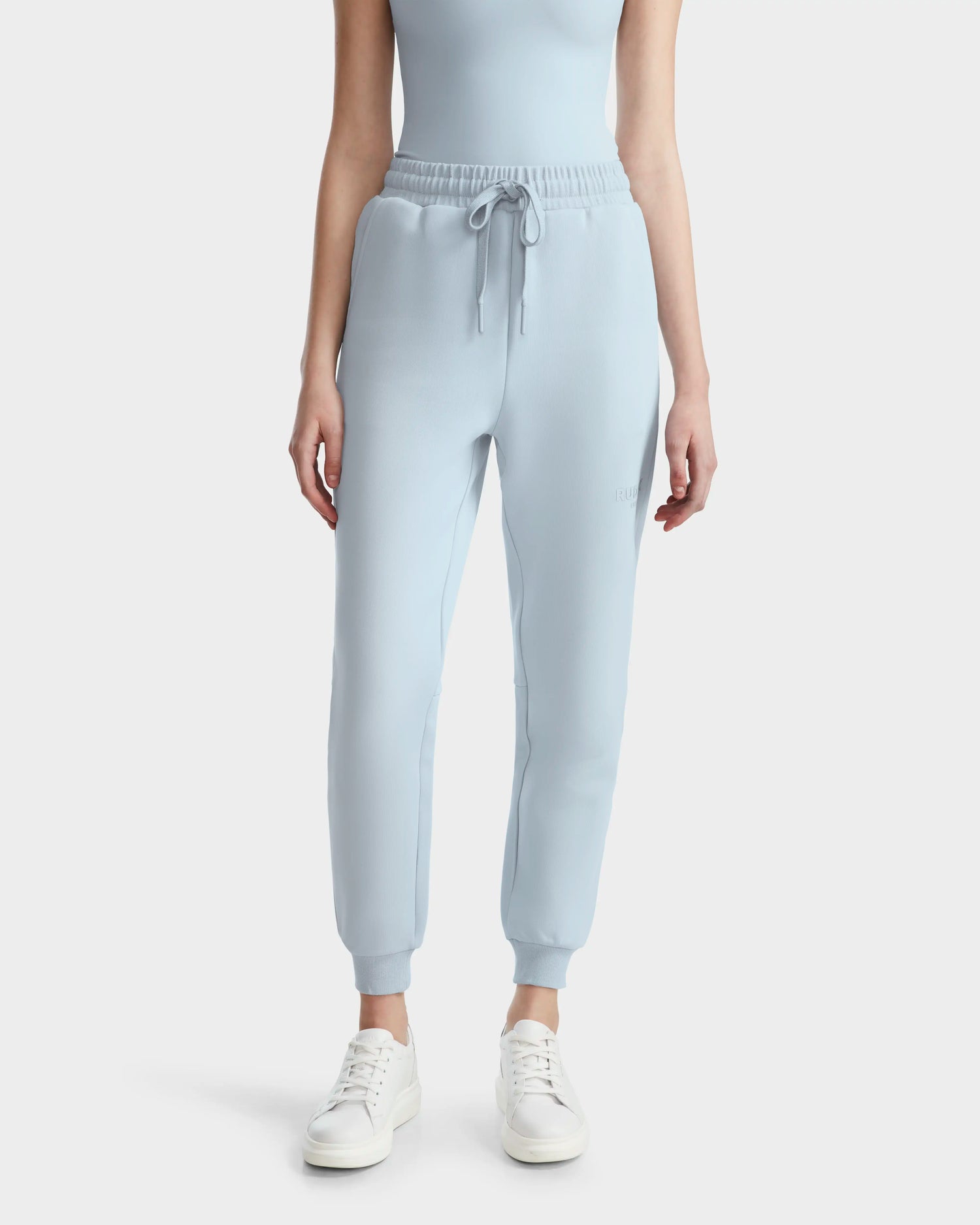 A person wears the JOSS - 9524009 Sky Blue W joggers with a matching sleeveless top and white sneakers, standing against a plain white background. The image is cropped just below the shoulders.