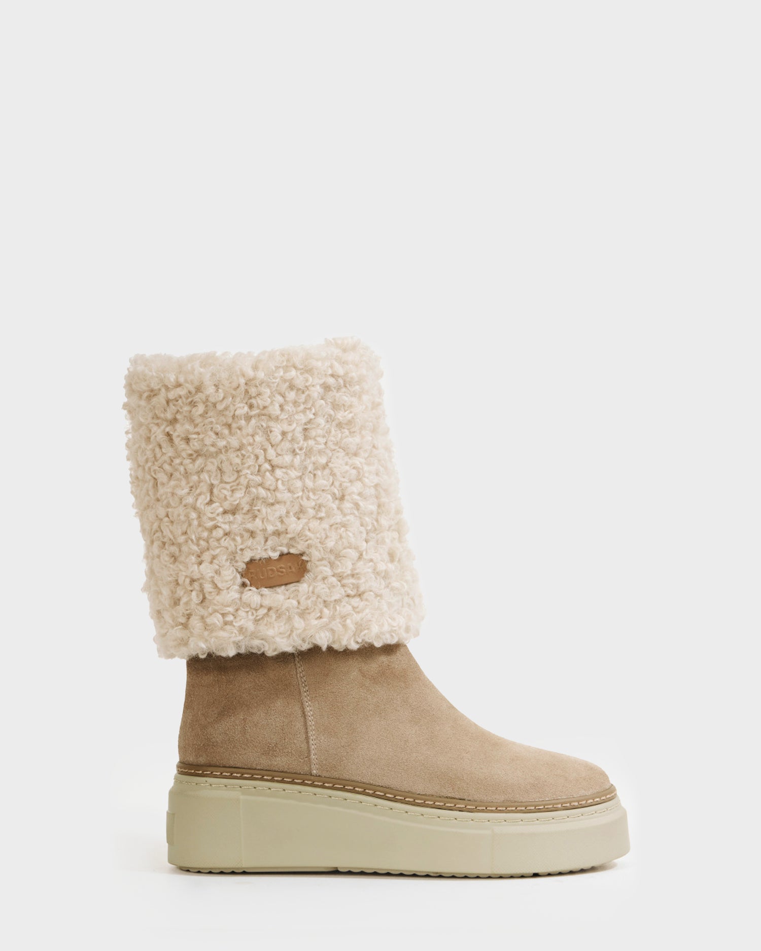 The Rudsak MIKIE - 8225579 Almond is a beige women’s suede boot with a chunky platform sole and a thick, textured cream foldover shearling cuff, shown against a plain white background.