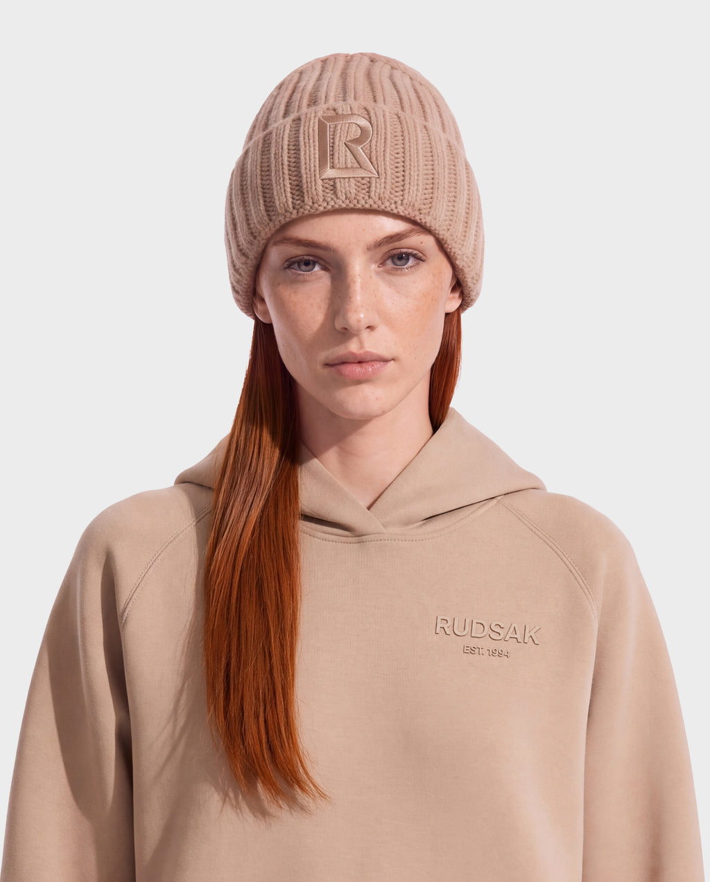 A person wears a ribbed camel-colored MISSA - 8426512 Camel beanie with a prominent letter R on the front.