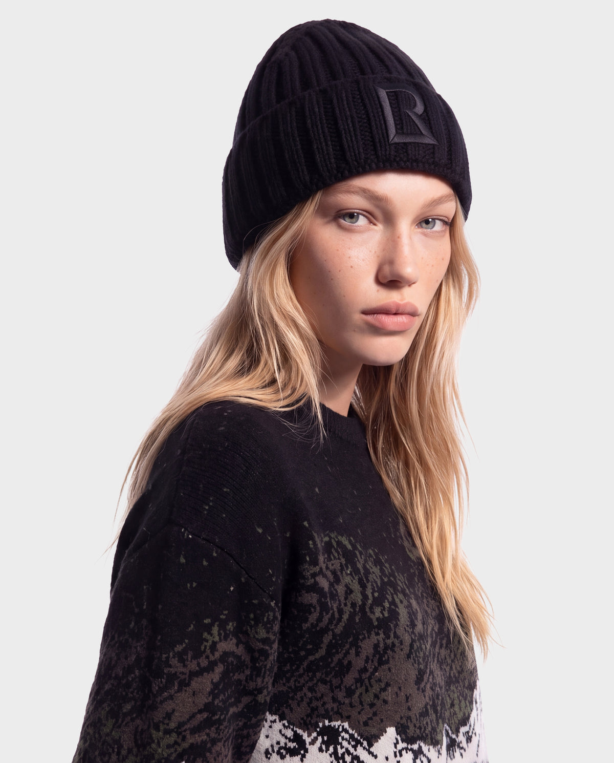 A person wearing a black Rudsak MISSA - 8426512 Black ribbed knit beanie featuring a square logo patch on the front.
