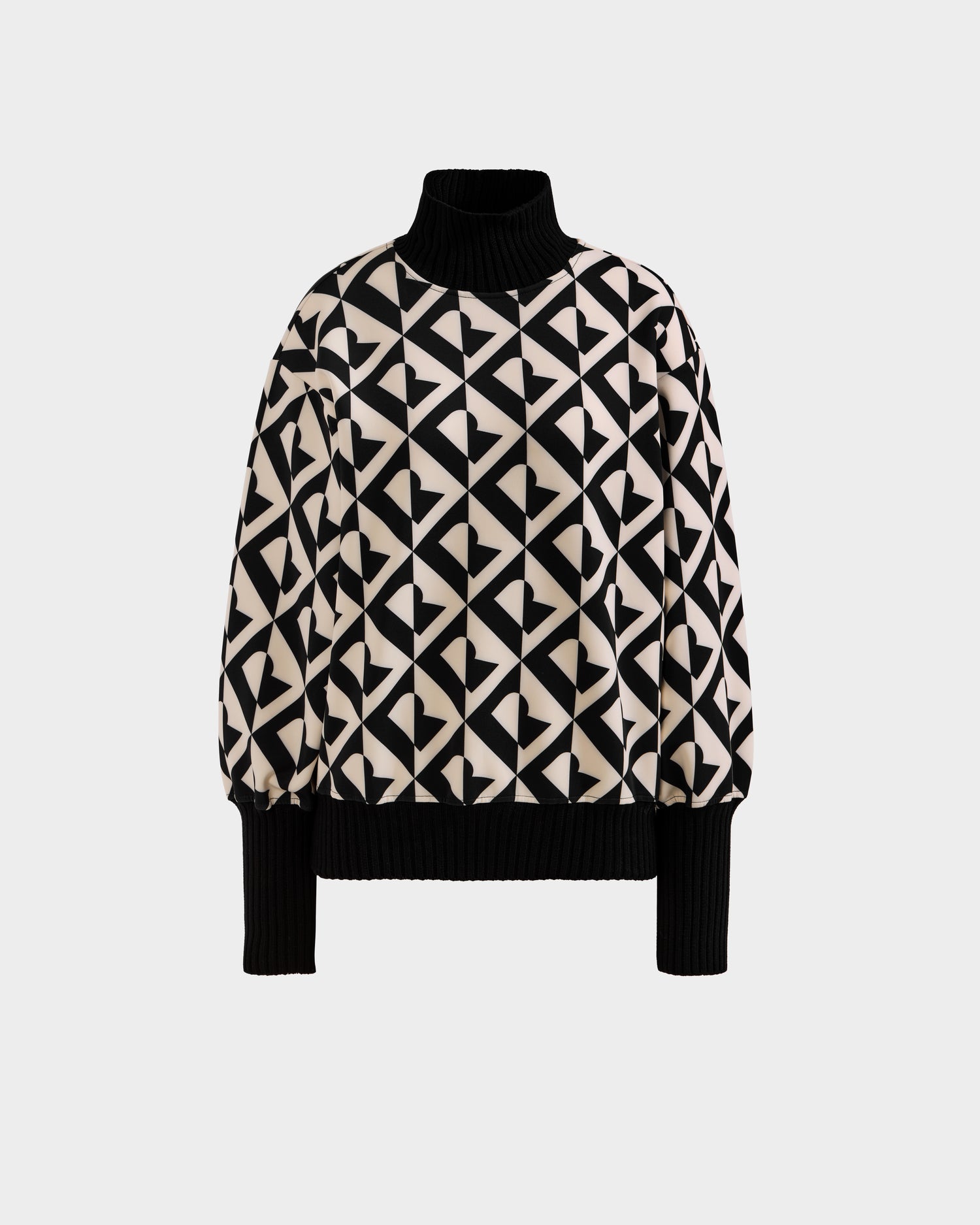 The Rudsak MAGGIE - 8525645 Vanilla Monogram is a long-sleeve, high-neck alpine sweater with black ribbed cuffs and hem, showcasing a bold black and beige geometric heart pattern on the body and sleeves.