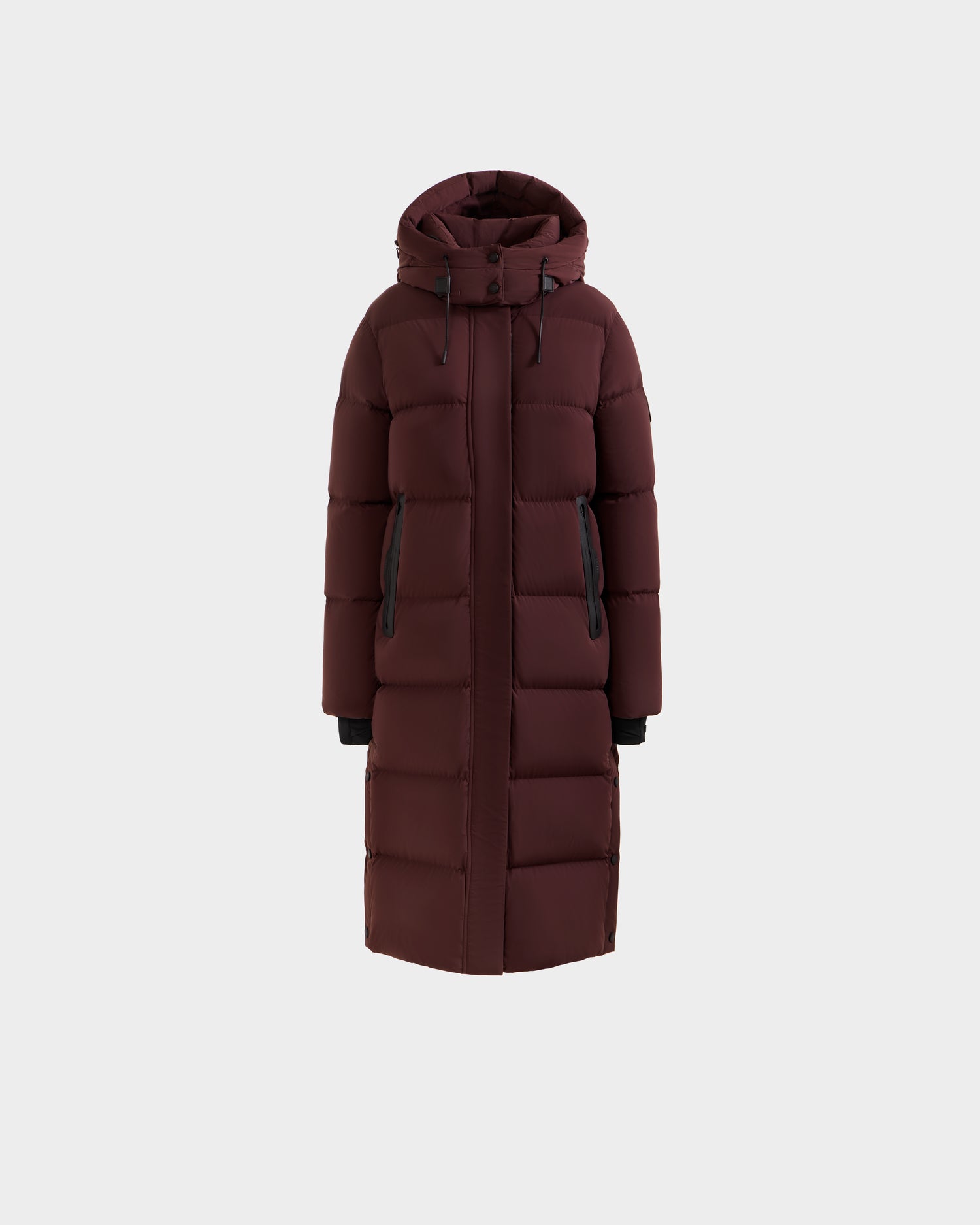 The Rudsak MAO - 8124780 Bordeaux is a women’s long down coat in maroon with RDS-certified down, a hood, front zipper, and black-trimmed pockets and cuffs, shown on a plain light gray background.