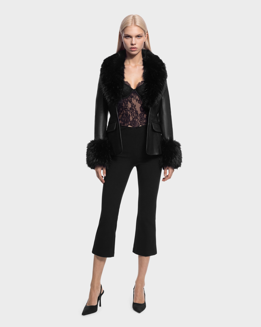A black Rudsak MARILLA - 8126972 Black jacket with a fur collar and fur-trimmed cuffs, worn over a black lace top and cropped trousers with black pumps.