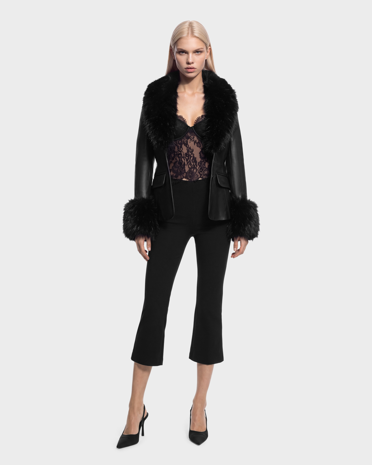 A black Rudsak MARILLA - 8126972 Black jacket with a fur collar and fur-trimmed cuffs, worn over a black lace top and cropped trousers with black pumps.