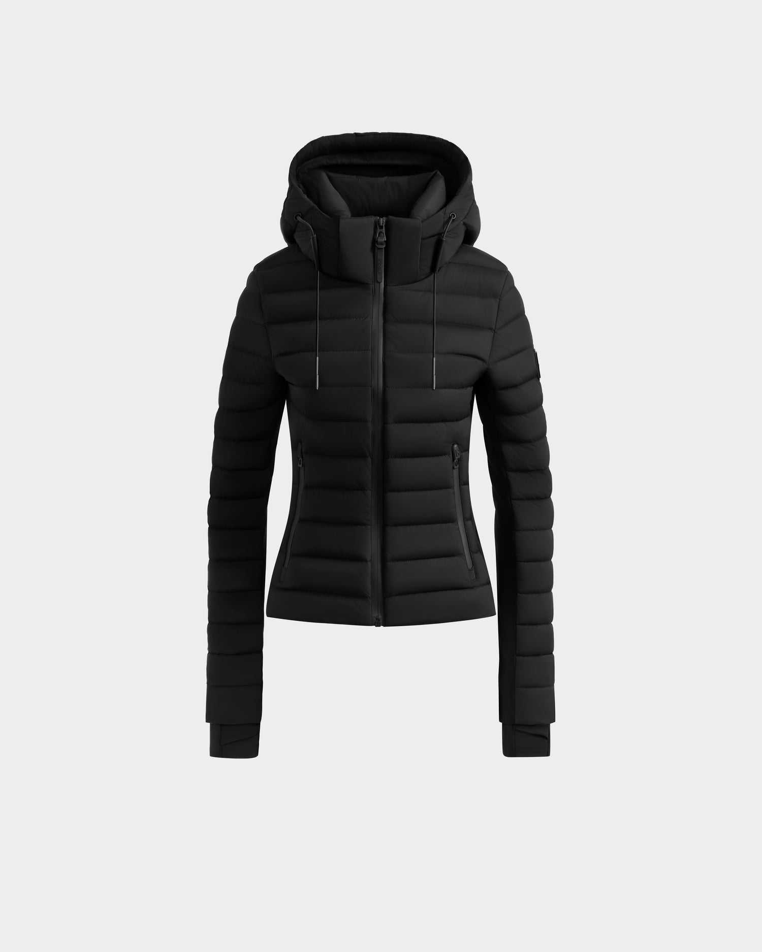 The Rudsak MARYA M - L125509 Black is a fitted women’s down puffer jacket with horizontal quilting, front zipper, two side zip pockets, and a drawstring hood. Made from wind and water-repellent fabric, shown on a plain light gray background.