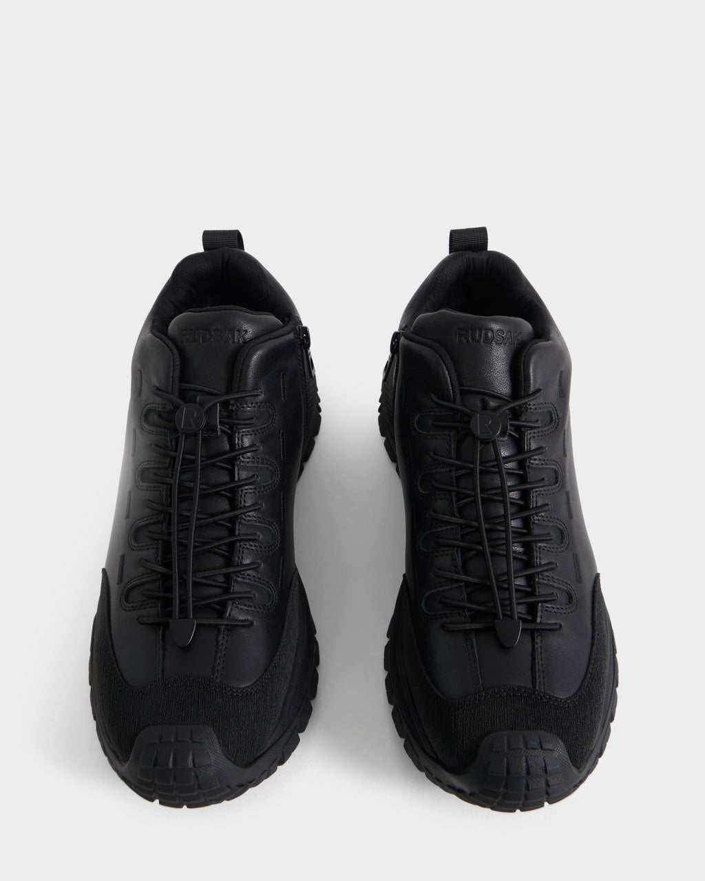 A pair of Rudsak MAX - 6226502 Black men’s sneakers with thick soles and crisscross laces, showcasing a utility-inspired design, are displayed from above against a plain white background.