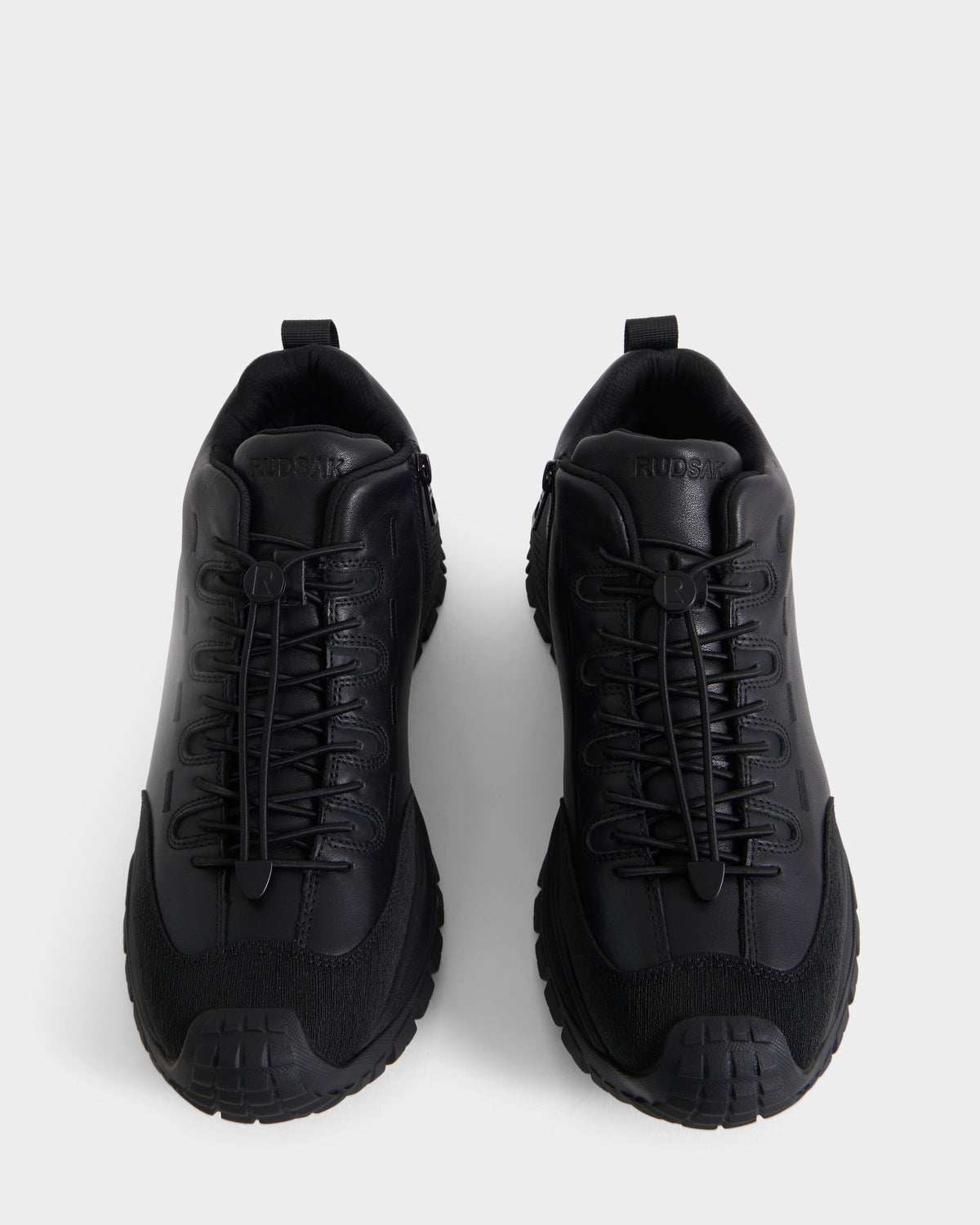 A pair of Rudsak MAX - 6226502 Black men’s sneakers with thick soles and crisscross laces, showcasing a utility-inspired design, are displayed from above against a plain white background.