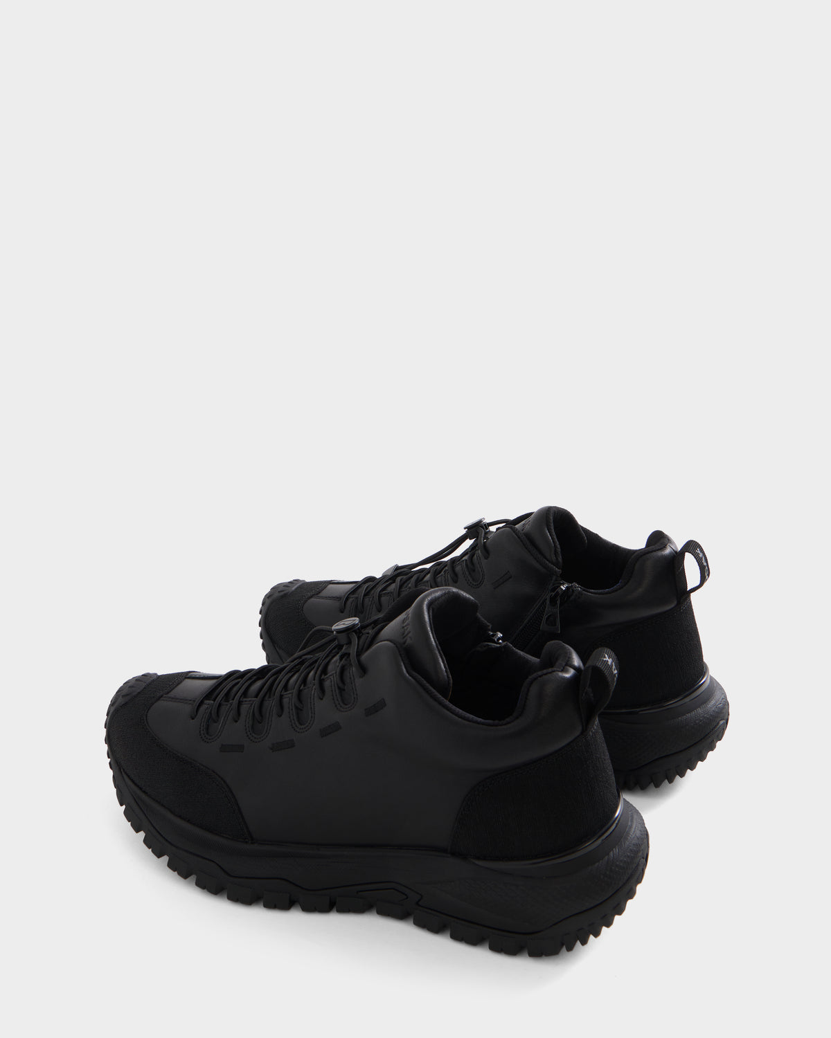 A pair of Rudsak MAX - 6226502 Black utility-inspired athletic sneakers with rugged soles, distinctive side detailing, and black laces, displayed against a plain white background.