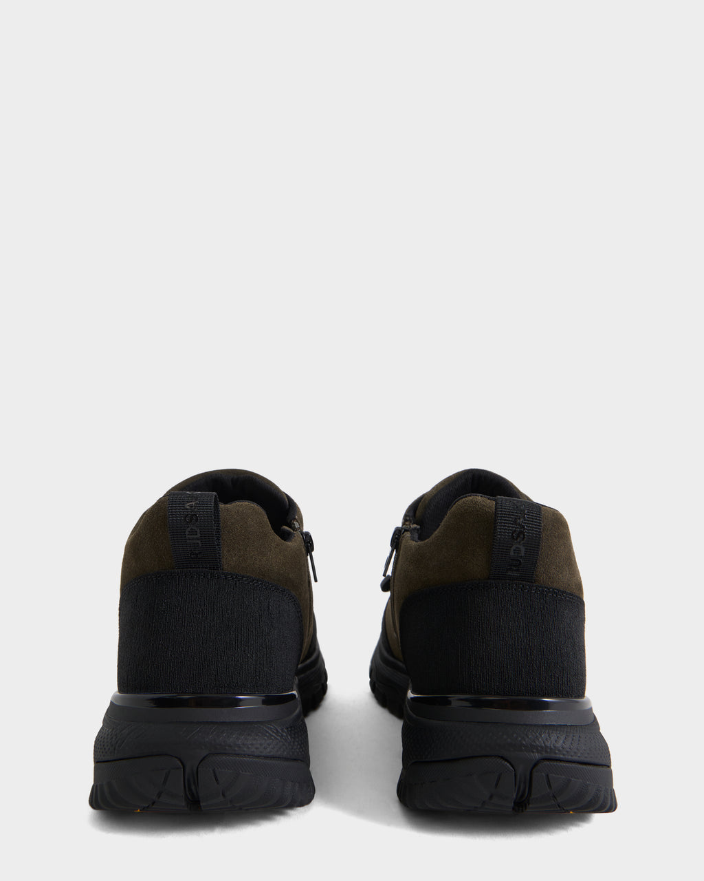 The Rudsak MAX S - 6226505 Olive men’s sneakers are displayed from the back on a plain white background. These shoes combine black and dark green tones with thick black soles, black pull tabs on the heels, and subtle suede accents for added texture. Their trail-inspired design lends a rugged yet stylish edge.