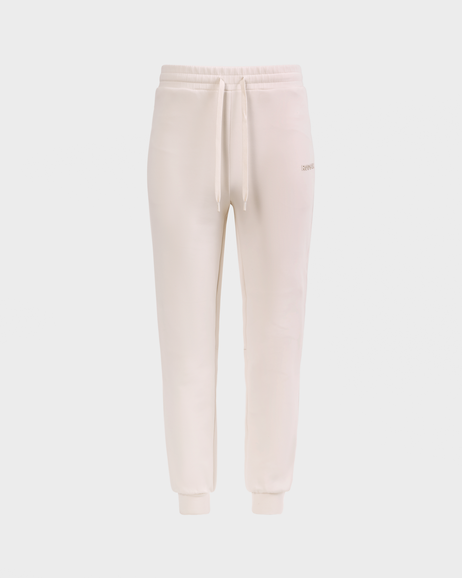 The Rudsak MAXTON - U525007 Vanilla W are cream cotton-blend joggers with an elastic waistband, drawstring ties, side pockets, and ribbed cuffs for everyday comfort, shown on a plain white background.