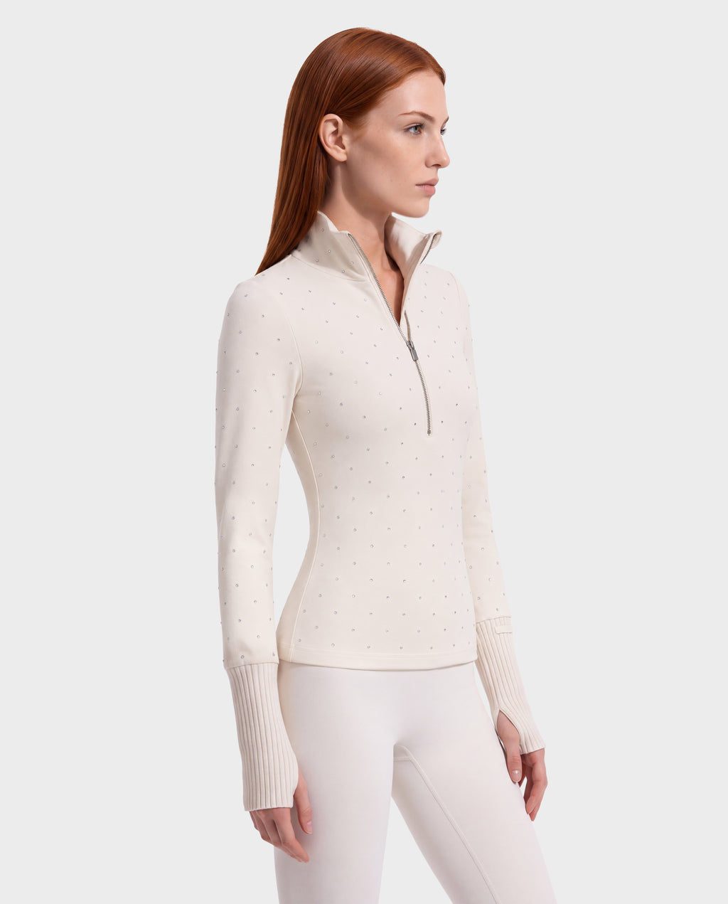 A model wearing the Rudsak NEVA - 8526524 Vanilla, a stretch nylon, cream-colored, quarter-zip après-ski top embellished with small crystals and featuring ribbed cuffs with thumbholes.