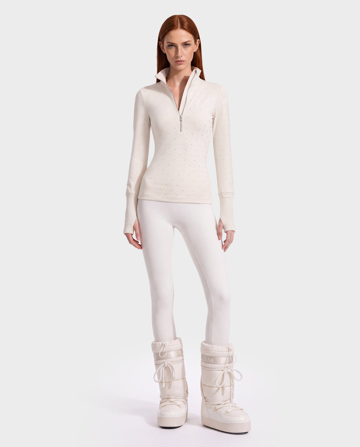 A model wearing a NEVA - 8526524 Vanilla crystal-scattered thermal long-sleeve quarter-zip top, white leggings, and chunky white winter boots.