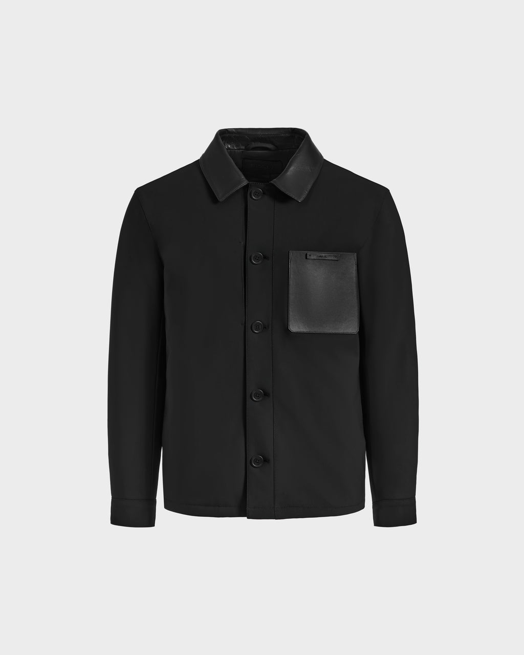 The PALMER - 6125002 Black by Rudsak is a modern black shirt jacket with a classic collar and a large leather patch pocket on the left chest, shown against a plain light gray background.