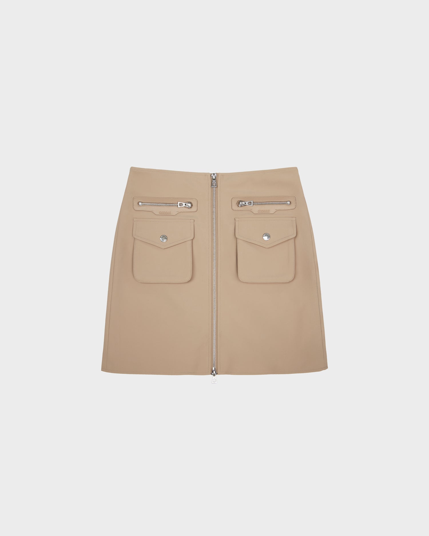 The PAMINA - 8525025 Almond mini skirt by Rudsak is made from beige vegan leather, designed with two utility flap pockets, two zippered pockets above them, and a bold front zipper. Shown against a plain white background.