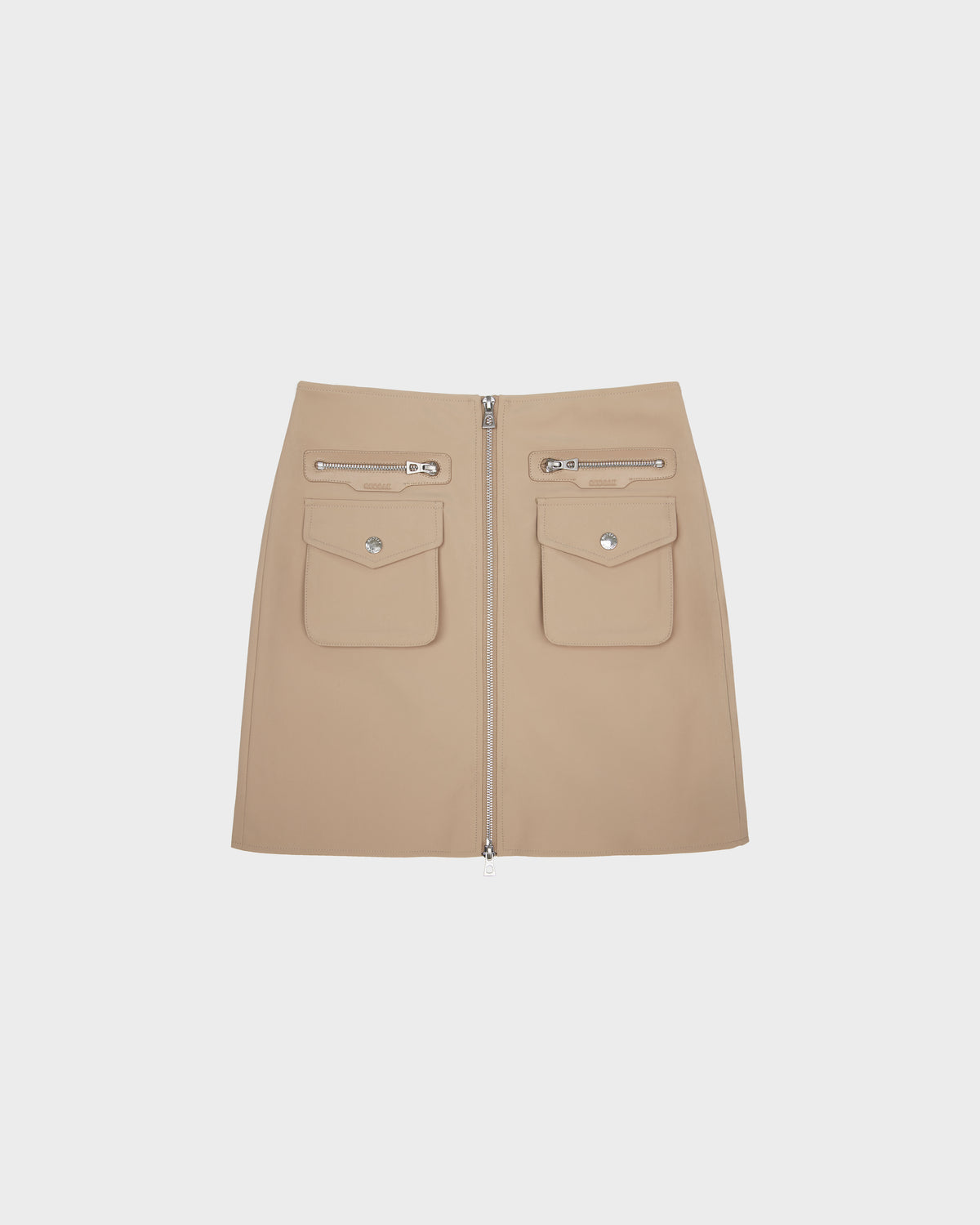 The PAMINA - 8525025 Almond mini skirt by Rudsak is made from beige vegan leather, designed with two utility flap pockets, two zippered pockets above them, and a bold front zipper. Shown against a plain white background.