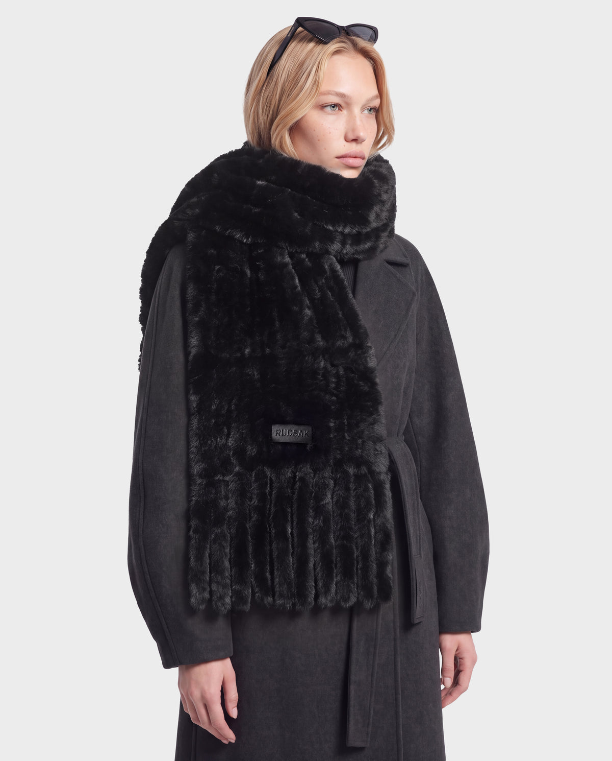 A person wearing a long black TAVIA - 8426511 Black coat and a luxurious faux-fur scarf with fringe detail.