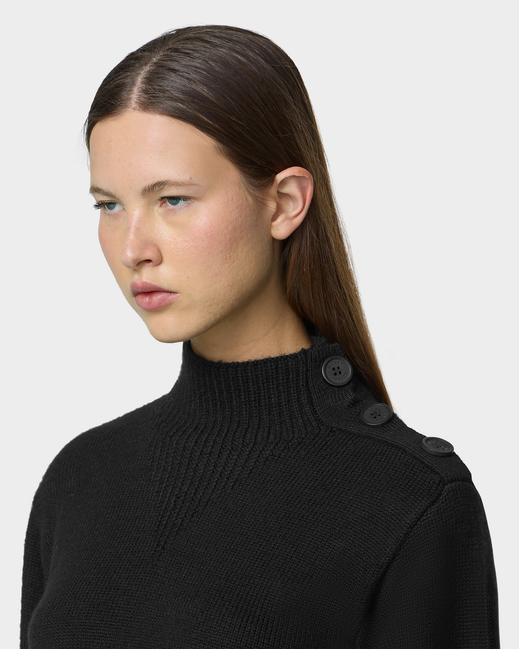 A person wearing a TATIANA - 8526694 Black ribbed mock-neck sweater with decorative buttons along the left shoulder.