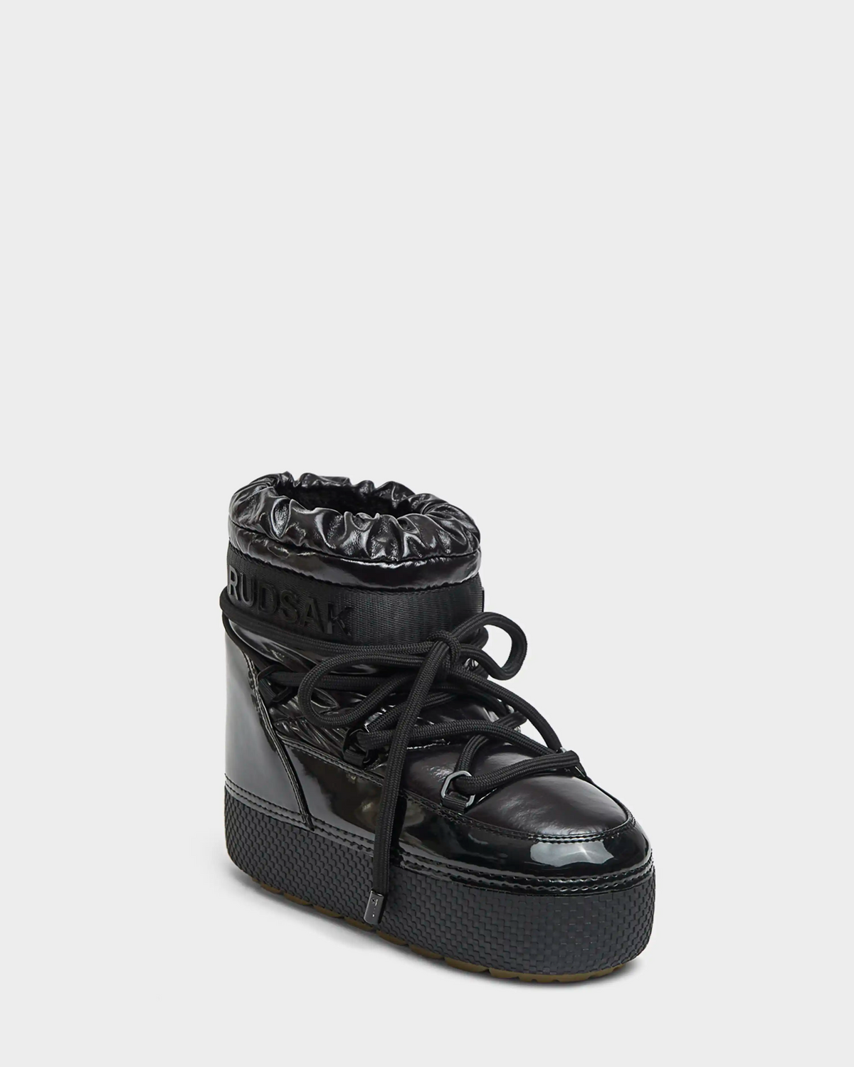 The MACE - 8223500 Black moon boot for women by Rudsak features a shiny black finish, thick laces, padded drawstring collar, faux fur lining, and the Rudsak logo on the side, set against a plain light grey background.