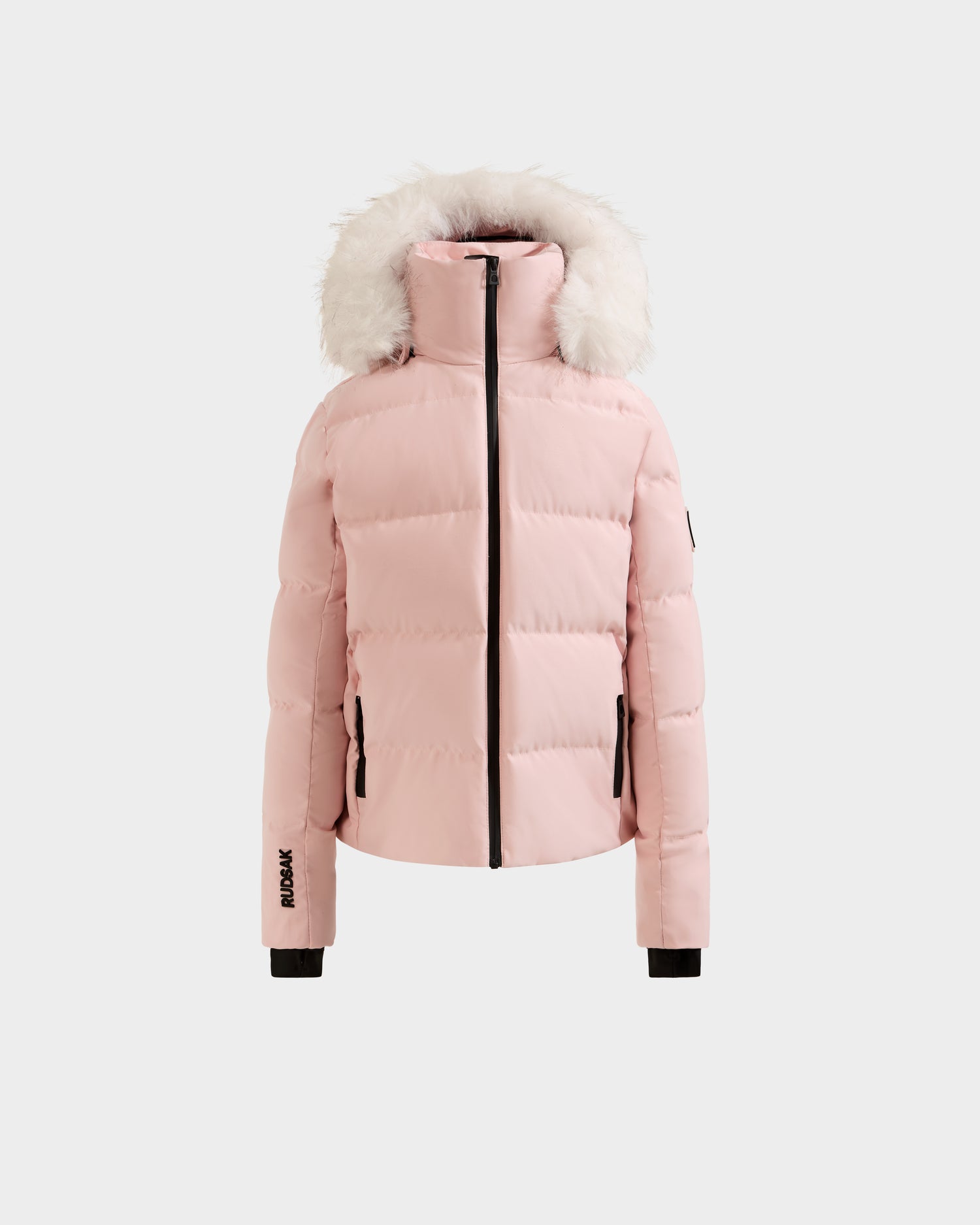 The Rudsak RAEGAN - 0125503 Pastel Pink is a light pink puffer jacket featuring a high collar, front zipper, detachable hood with white faux fur trim, black cuffs, and zippered side pockets, shown on a plain white background.