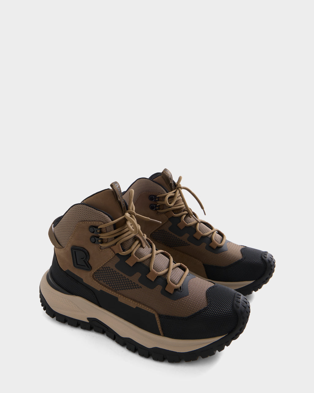 A pair of REXON - 6226503 Cement high-top winter sneaker boots by RUDSAK, featuring brown and black uppers with beige laces, thick rugged soles, striking angular patterns, and black logo detailing on the side.