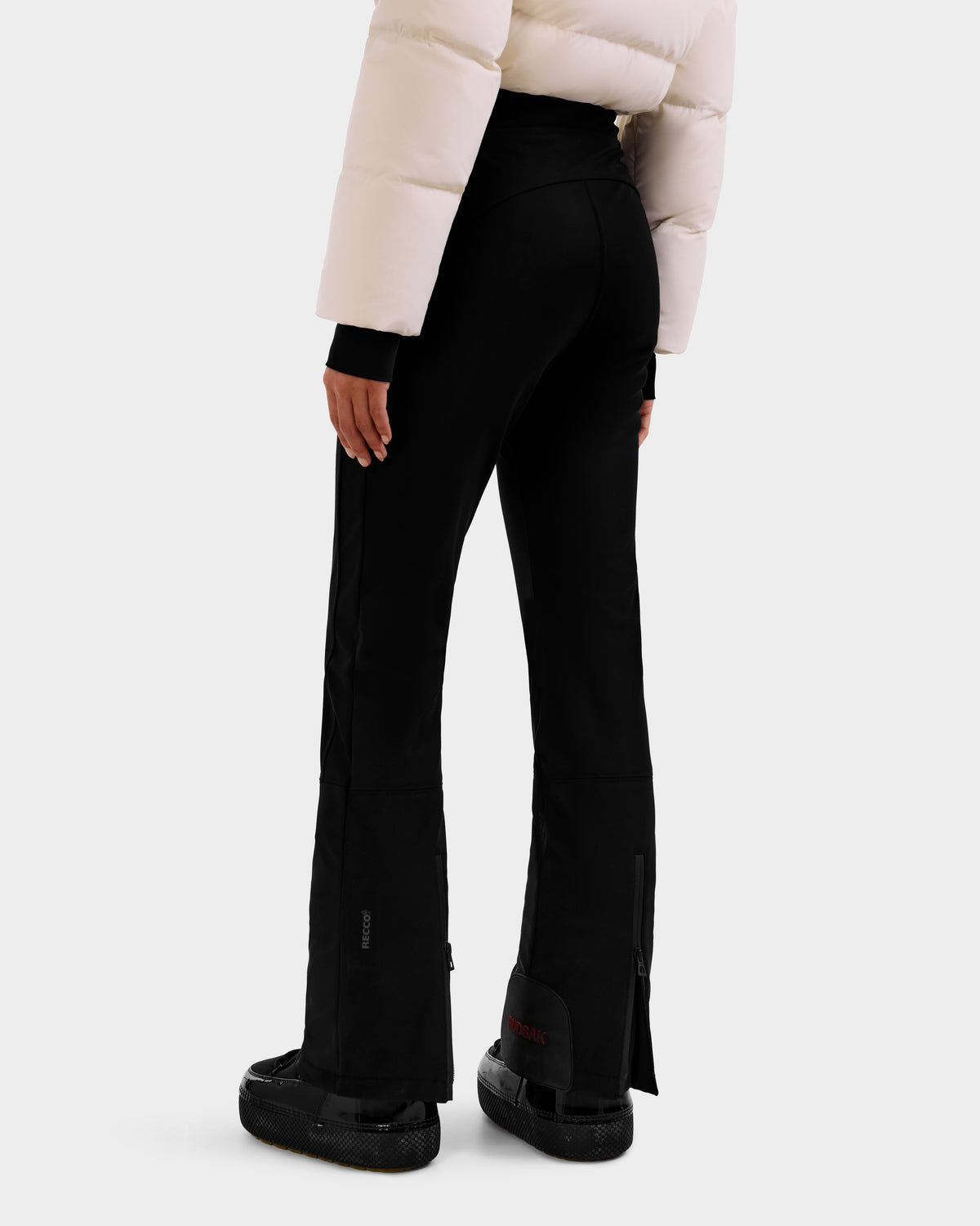 A person wearing the Rudsak DINARA - 8125600 Vanilla puffer jacket with RECCO rescue technology, black flared pants, and black sneakers stands with their back to the camera against a plain white background.