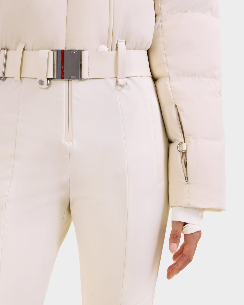 Wearing Rudsak's LOVE - 8124724 Vanilla ski suit, a person stands with one hand by their side—this stylish women's outfit is perfect for alpine adventures.