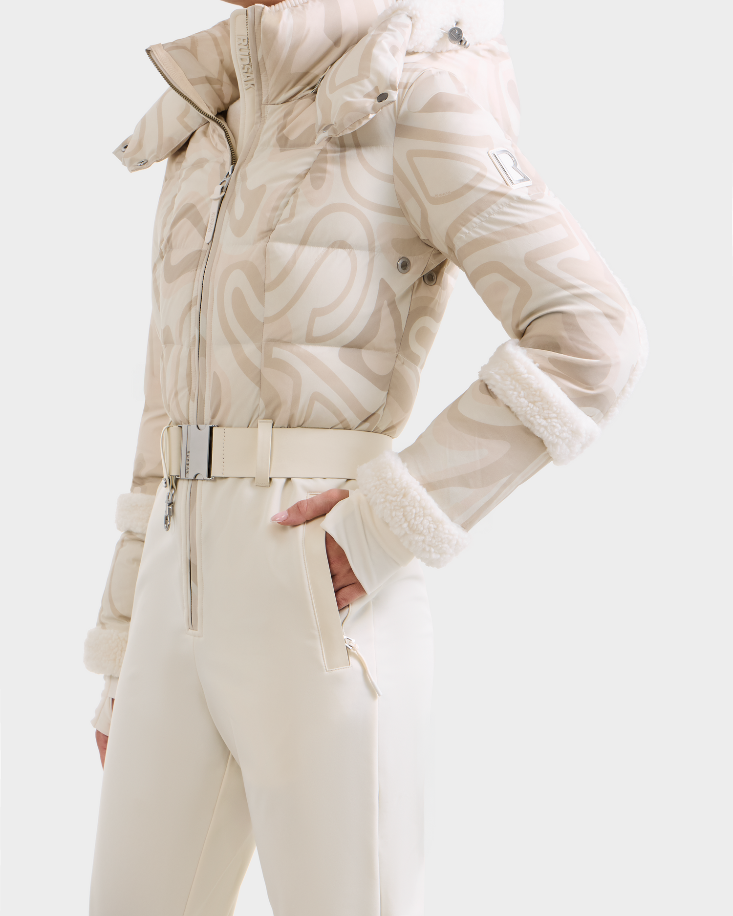 A model wears the Rudsak CARMEN P - 8125707 Vanilla Deja vu: a beige and white patterned puffer jacket with fur trim and matching pants. Available for pre-order, shipping by November 30th.