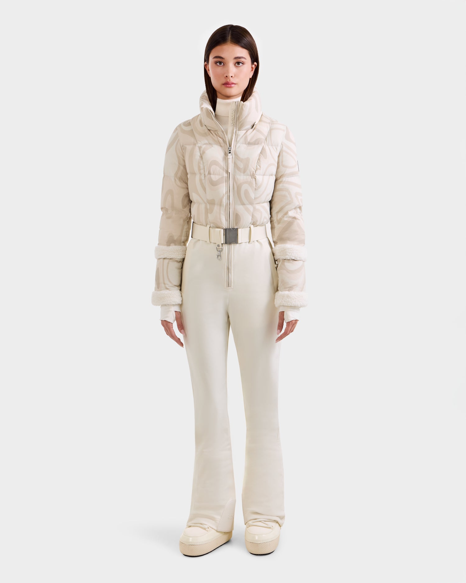 A woman faces forward in the Rudsak CARMEN P - 8125707 Vanilla Deja vu outfit: a chic cream quilted jacket, belted high-waisted pants, and platform shoes. Now available for pre-order; ships by November 30th.