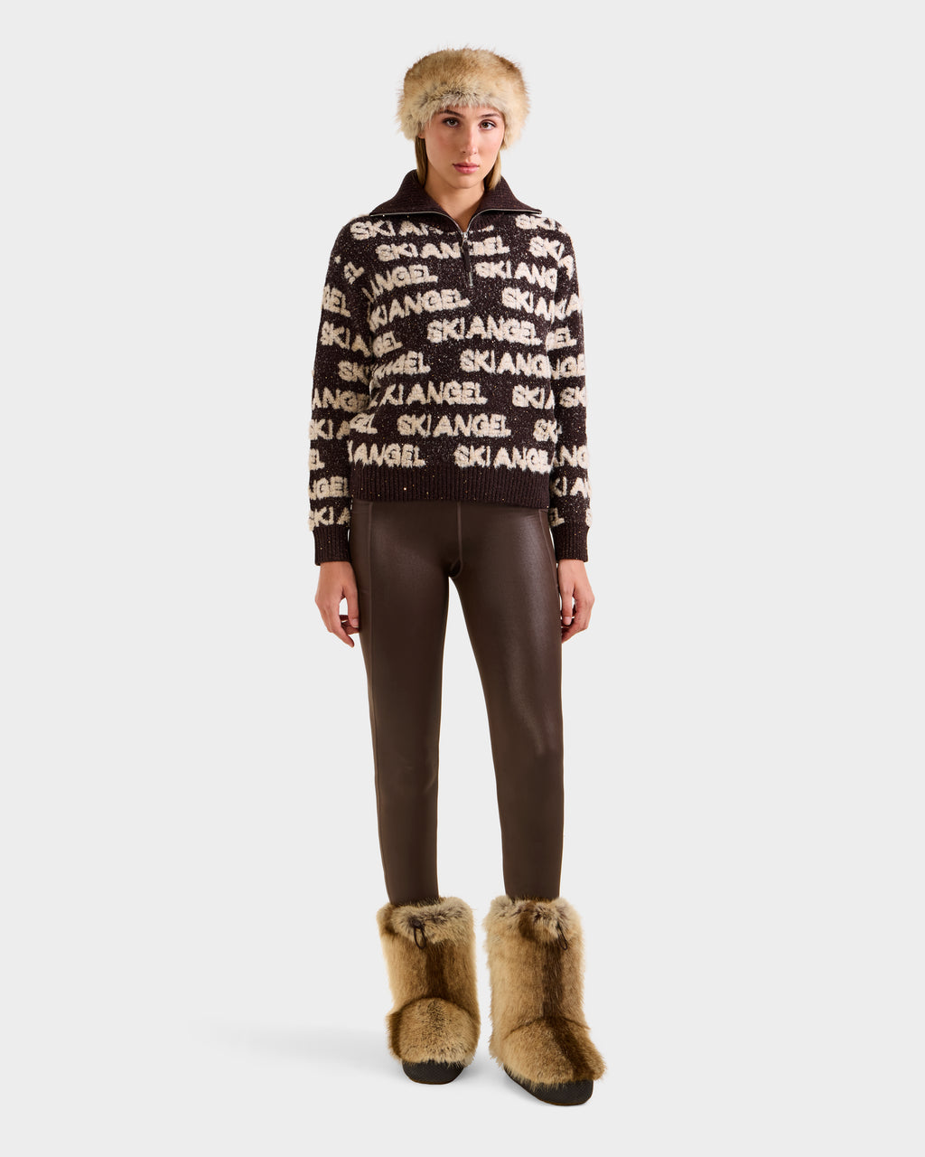 A person wears the Rudsak LYDIA - 8525687 Espresso sweater, brown leggings, a tan fur hat, and large tan fur boots while standing facing forward against a plain white background.