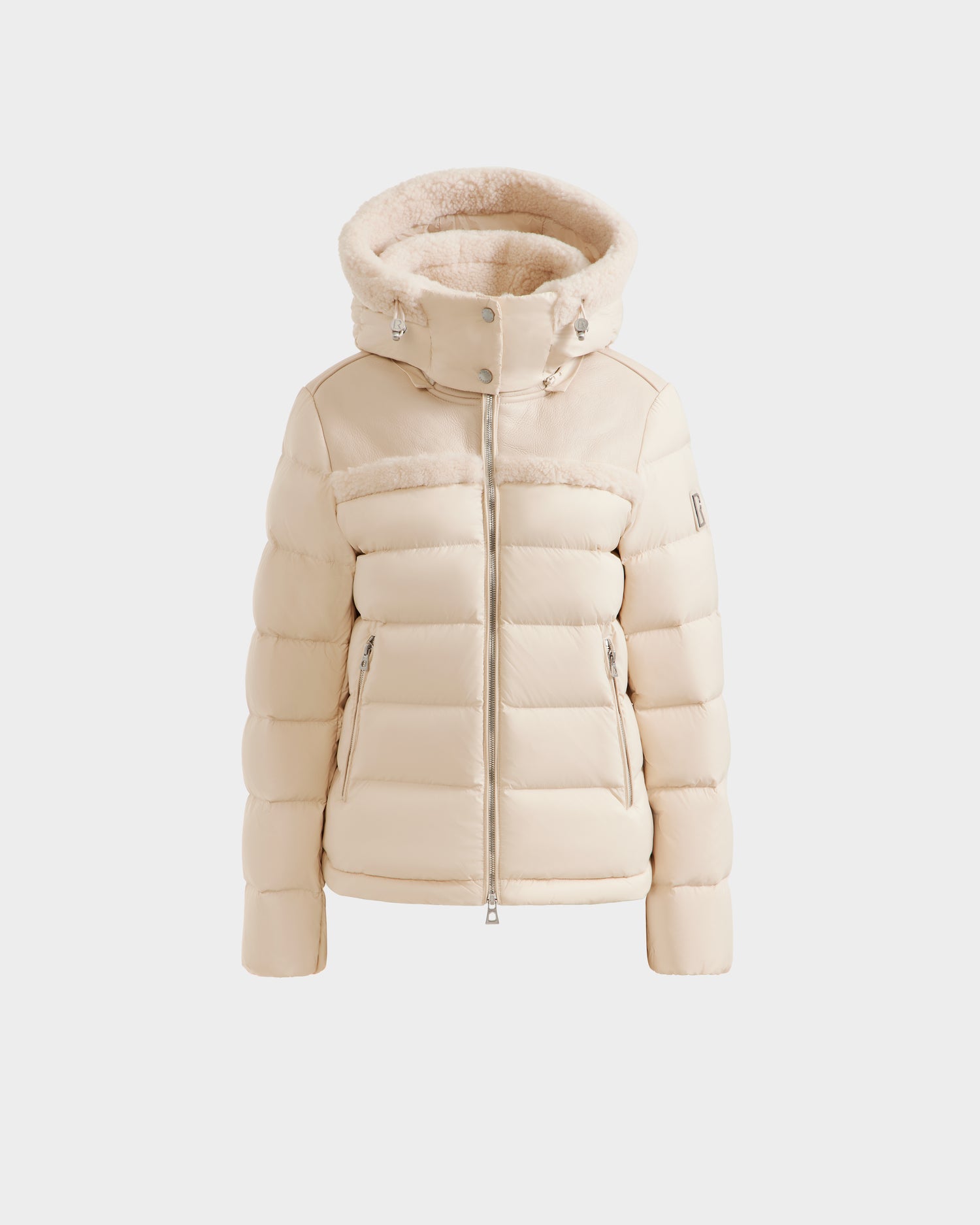 The Rudsak SANDRA - 8125612 Vanilla is a cream-colored shearling puffer jacket featuring a thick, fur-lined hood, front zipper, and side zip pockets, shown against a plain white background.