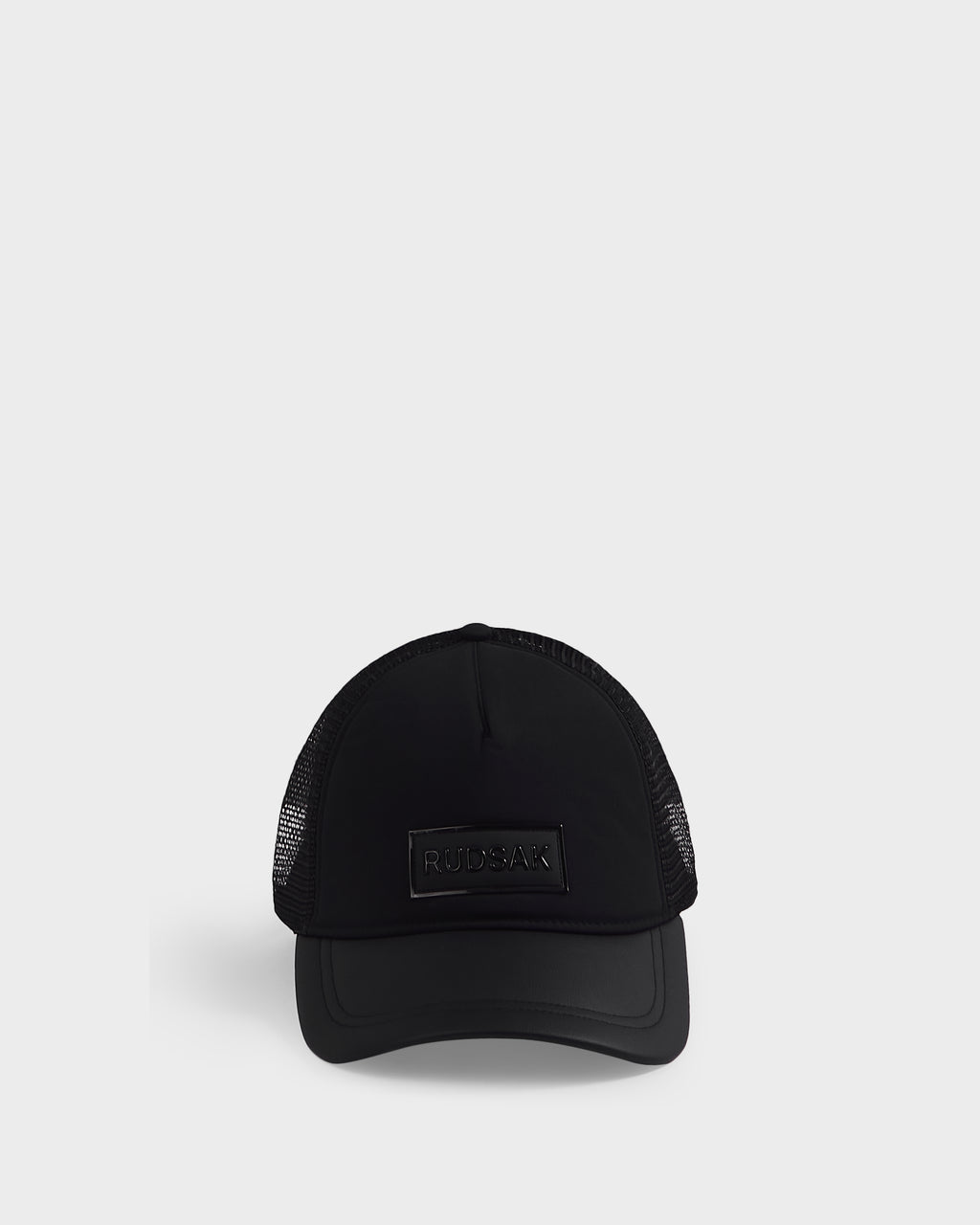 The FENIX - 9422522 Black by Rudsak is a black trucker cap with mesh sides and back, featuring a rectangular Rudsak logo patch on the front, shown against a plain white background.