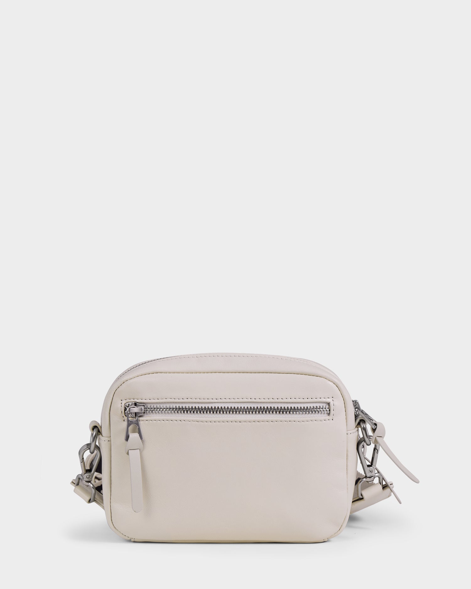 The Rudsak ZOYA L - 8325543 Vanilla is a small, light beige leather crossbody bag with silver hardware, front zip pocket, minimal design, and adjustable strap, shown on a plain white background.