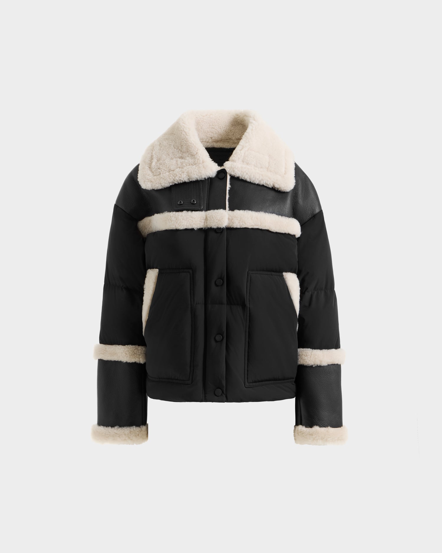 The SHIRLEY - 8125613 Black by Rudsak is a chic women’s down jacket with cream shearling trim on the collar, cuffs, pockets, chest, and sleeves. Shown on a white background, it’s perfect as a cropped winter coat.