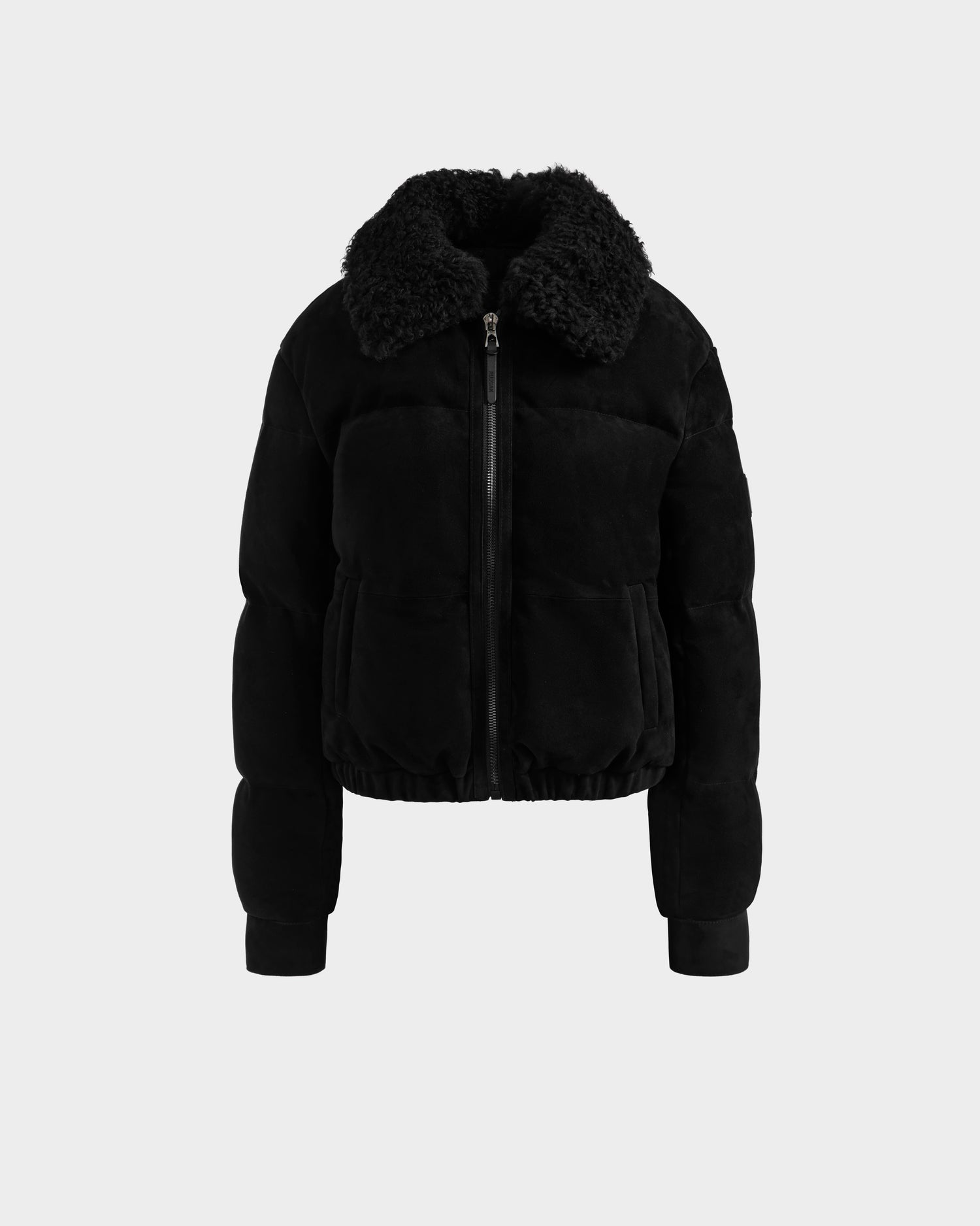 The Rudsak STACEY - 8125049 Black is a women’s black cropped puffer bomber jacket with a shearling collar, front zipper, long sleeves, and two front pockets, shown on a plain light gray background.