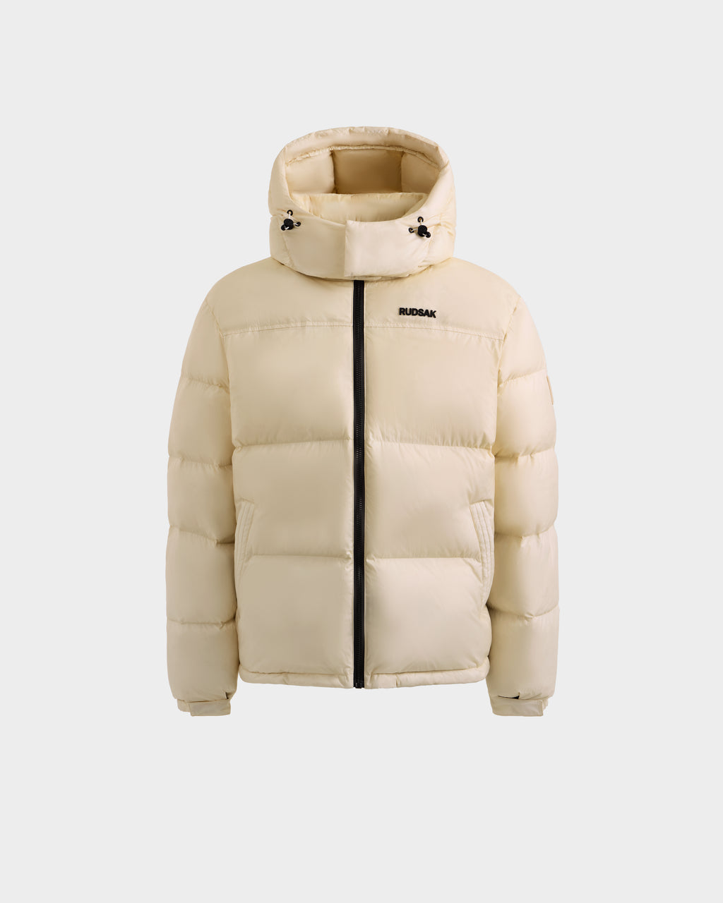 The Rudsak STEFANO - 6125574 Vanilla is a beige men’s quilted down puffer with a hood, black zipper, and small RUDSAK logo on the left chest, shown against a white background as quality winter outerwear.